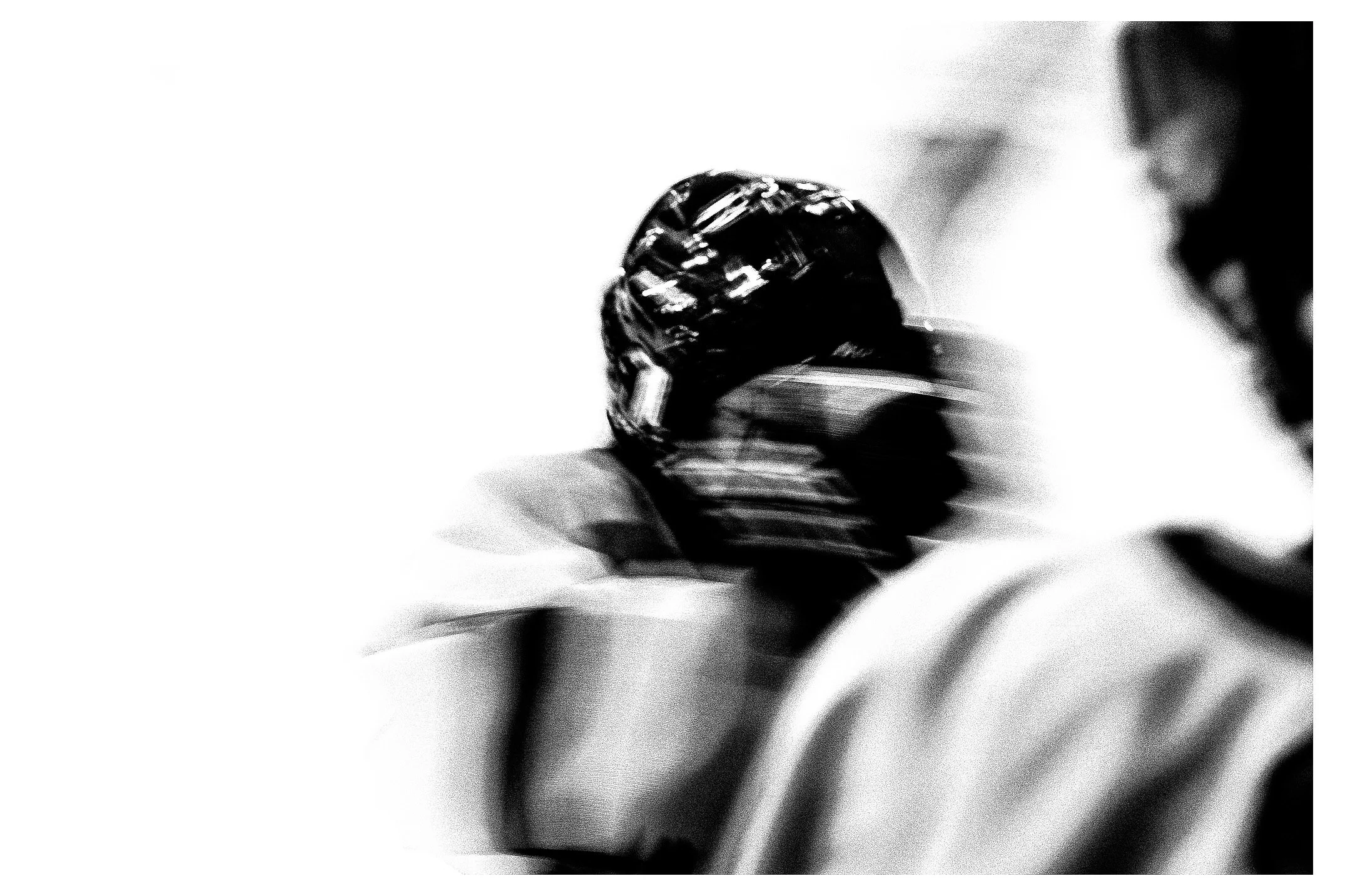 A black and white image of a person wearing a patterned headscarf, with blurred background.
