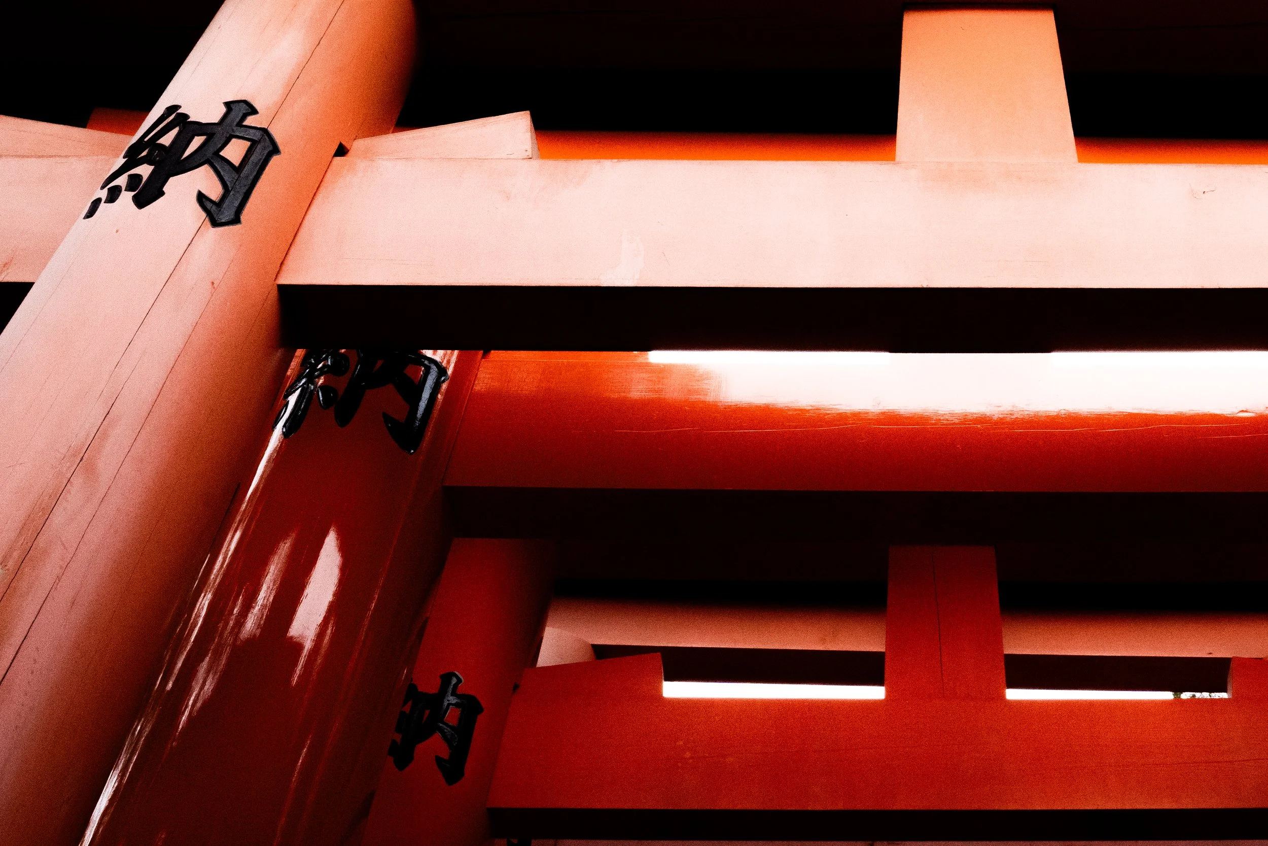 Close-up of red architectural beams and black Japanese characters on a red structure.