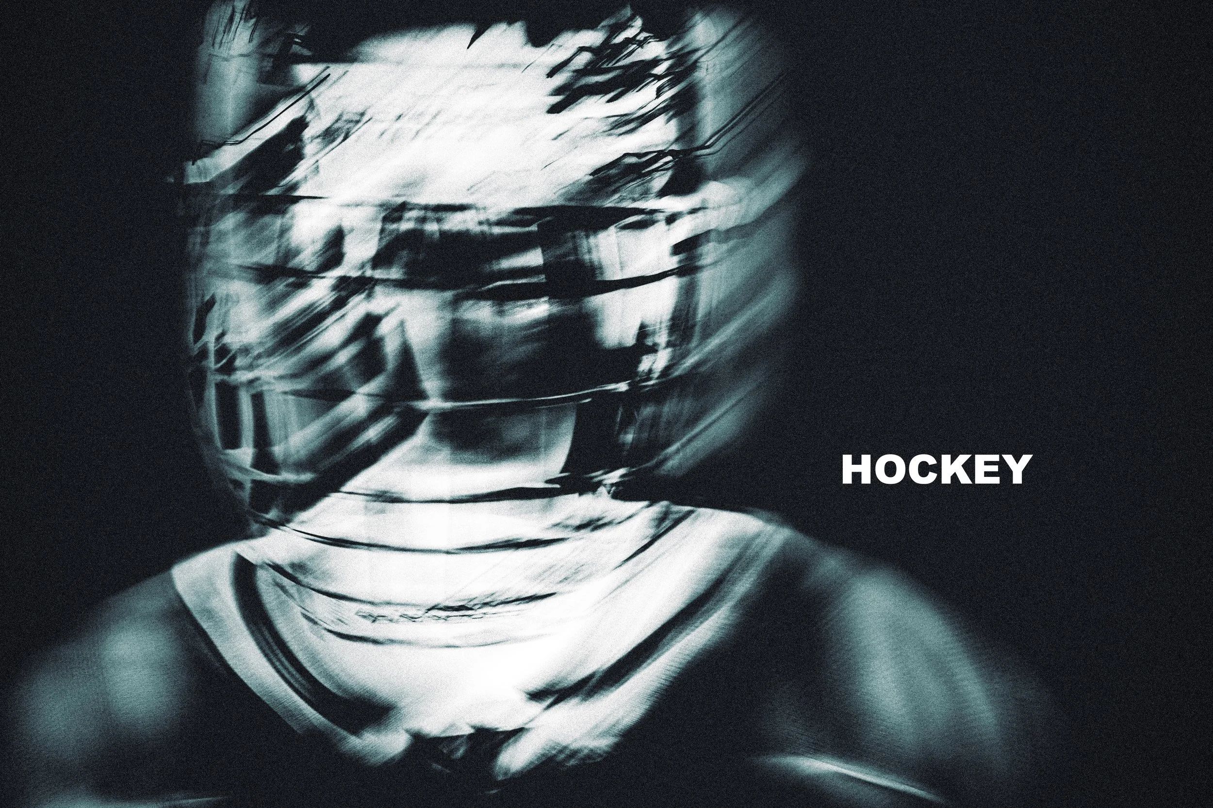 Blurred black and white image of a hockey goalie helmet with the word 'HOCKEY' written in white text in the lower right corner.