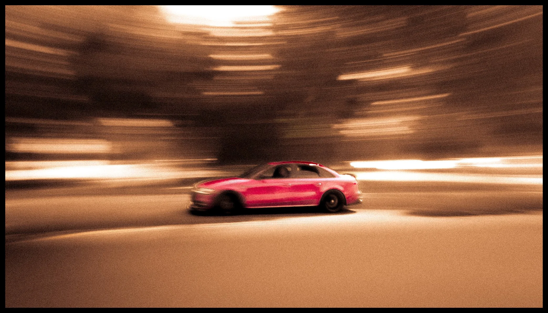 A pink sports car driving on a highway at night with blurred lights and trees in the background, indicating motion.