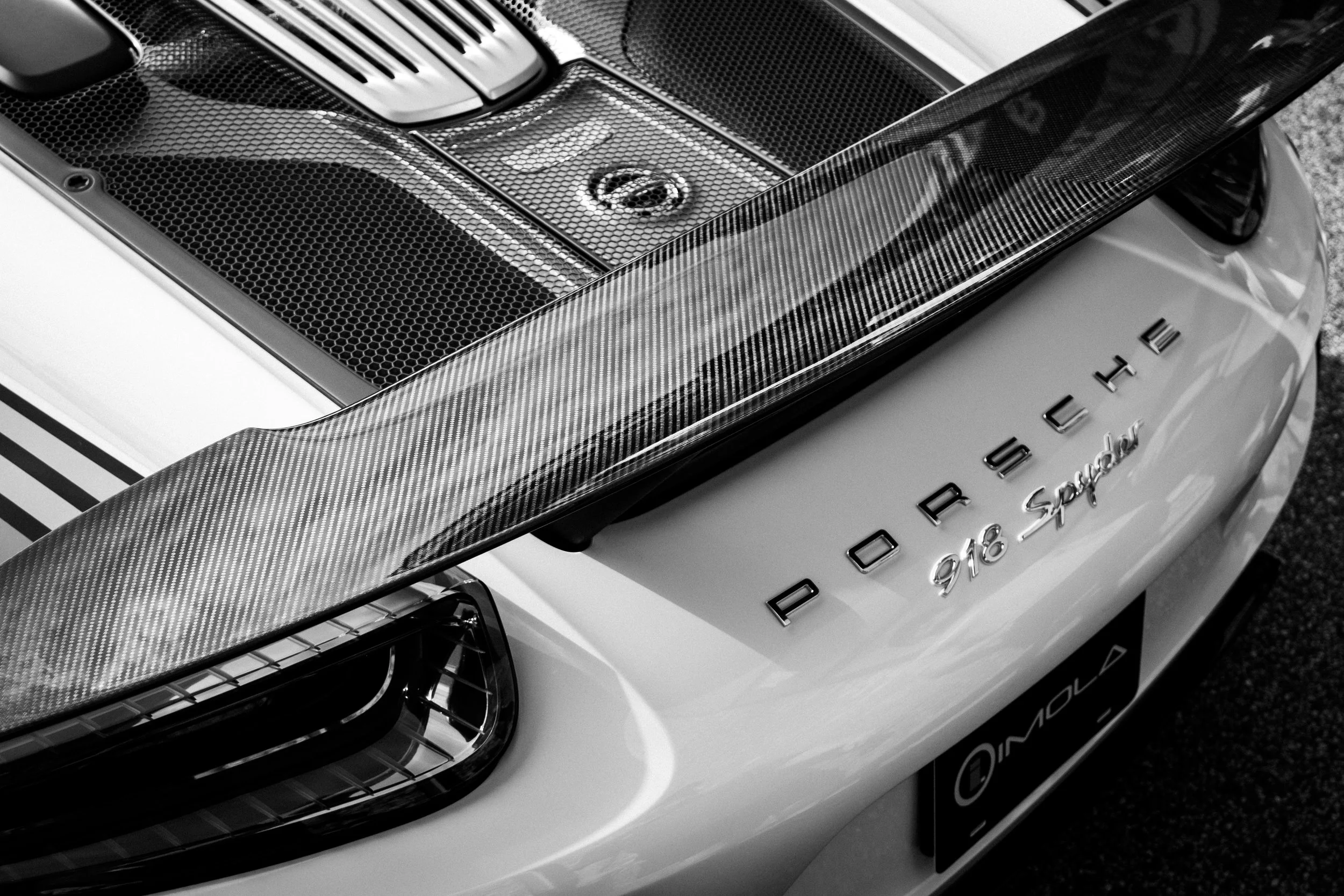 Close-up of a luxury Porsche 918 Spyder car with a carbon fiber hood and intricate mesh details.