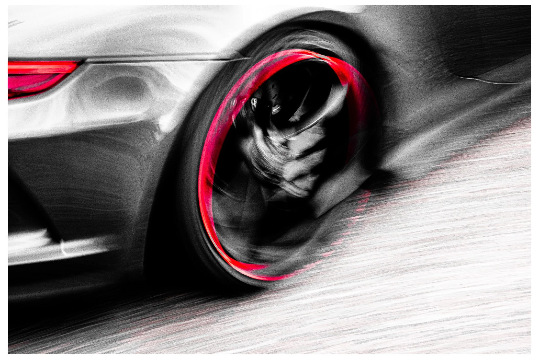 Close-up of a high-performance sports car tire moving at high speed, with blurred motion effects and a red accent on the tire's rim.