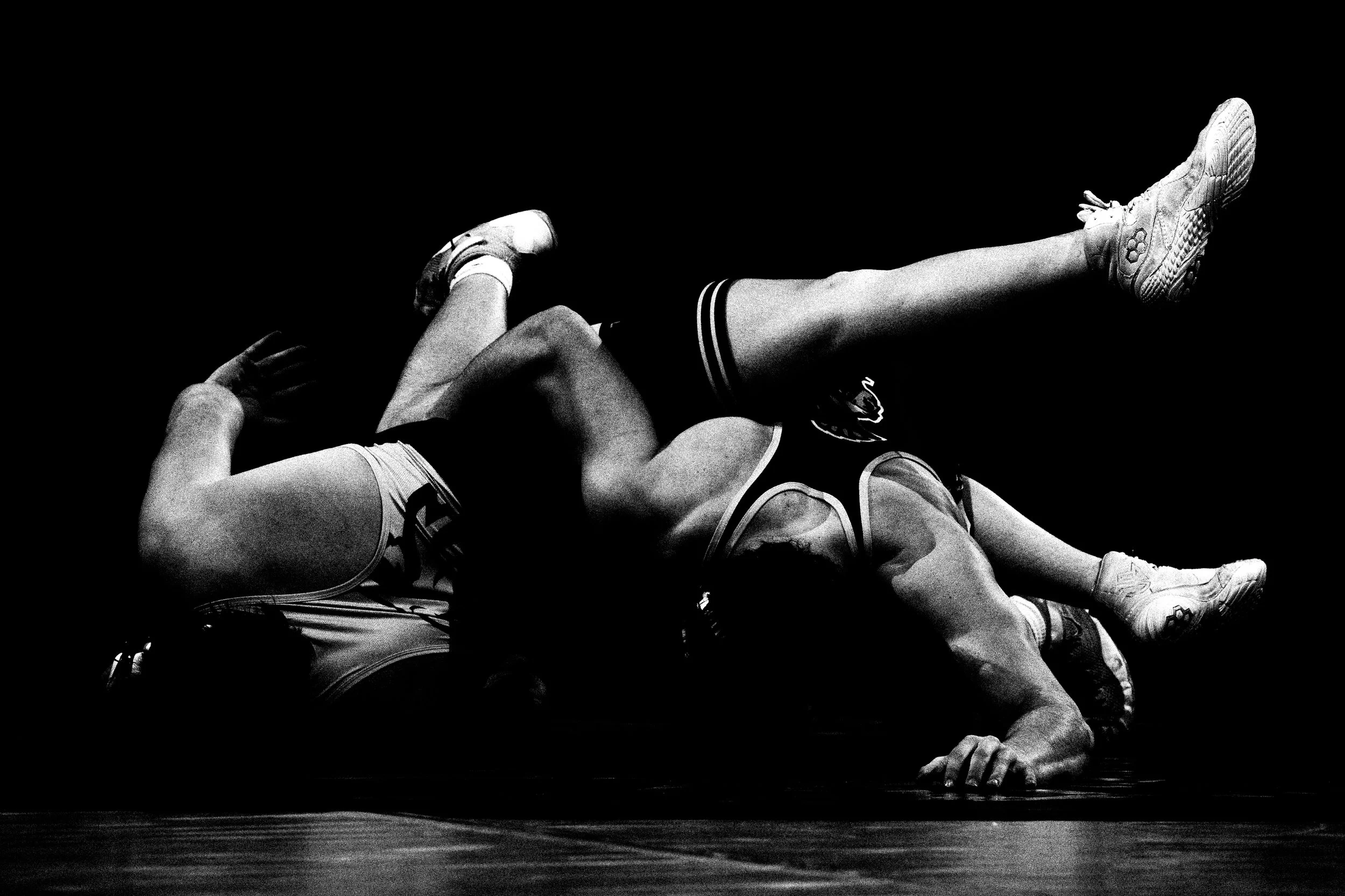 Black and white photo of two wrestlers on a mat, one pinning the other.