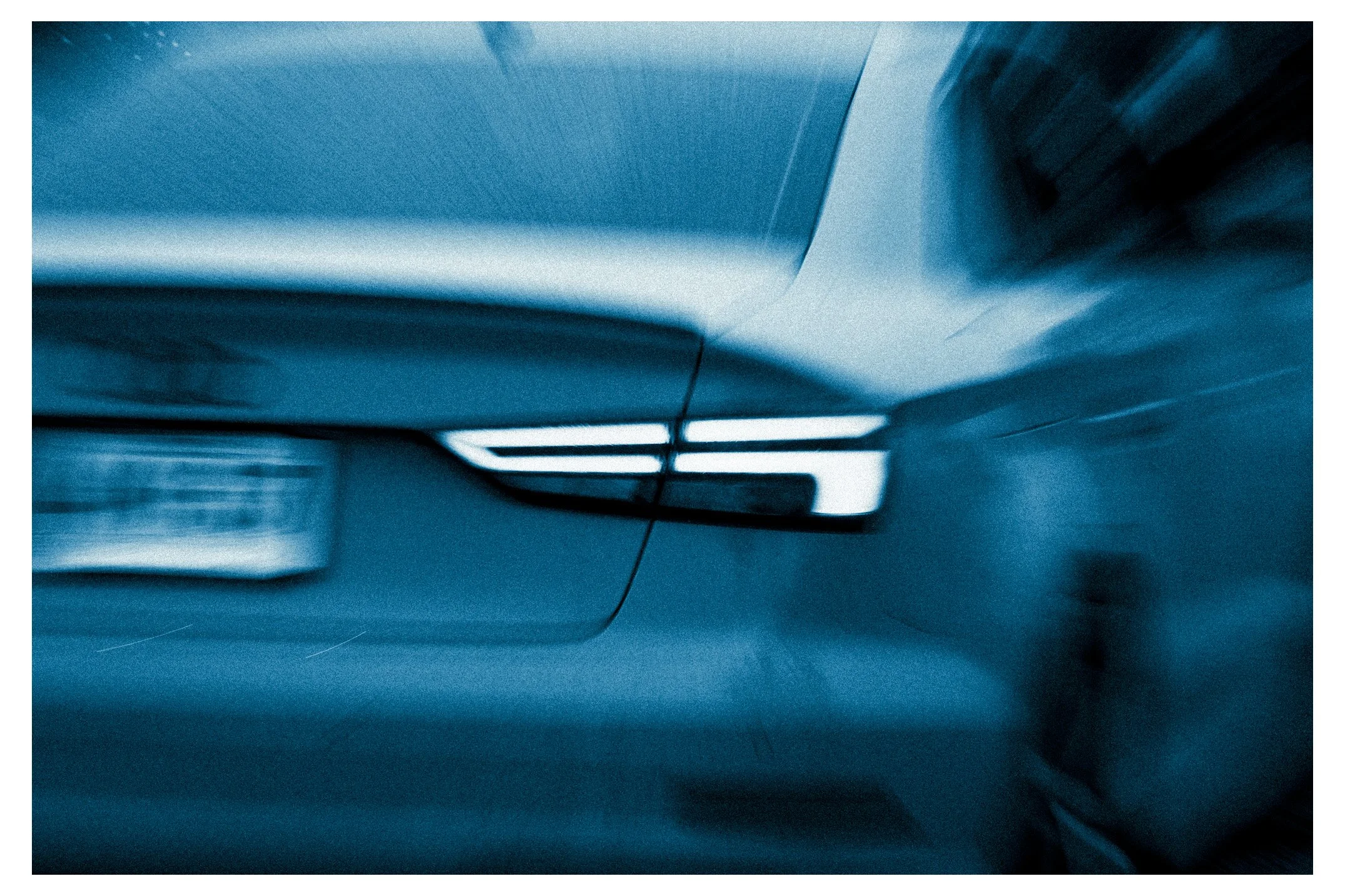 Close-up view of a metallic surface with a handle, possibly from a kitchen appliance or door, with blurred background in shades of blue and black.