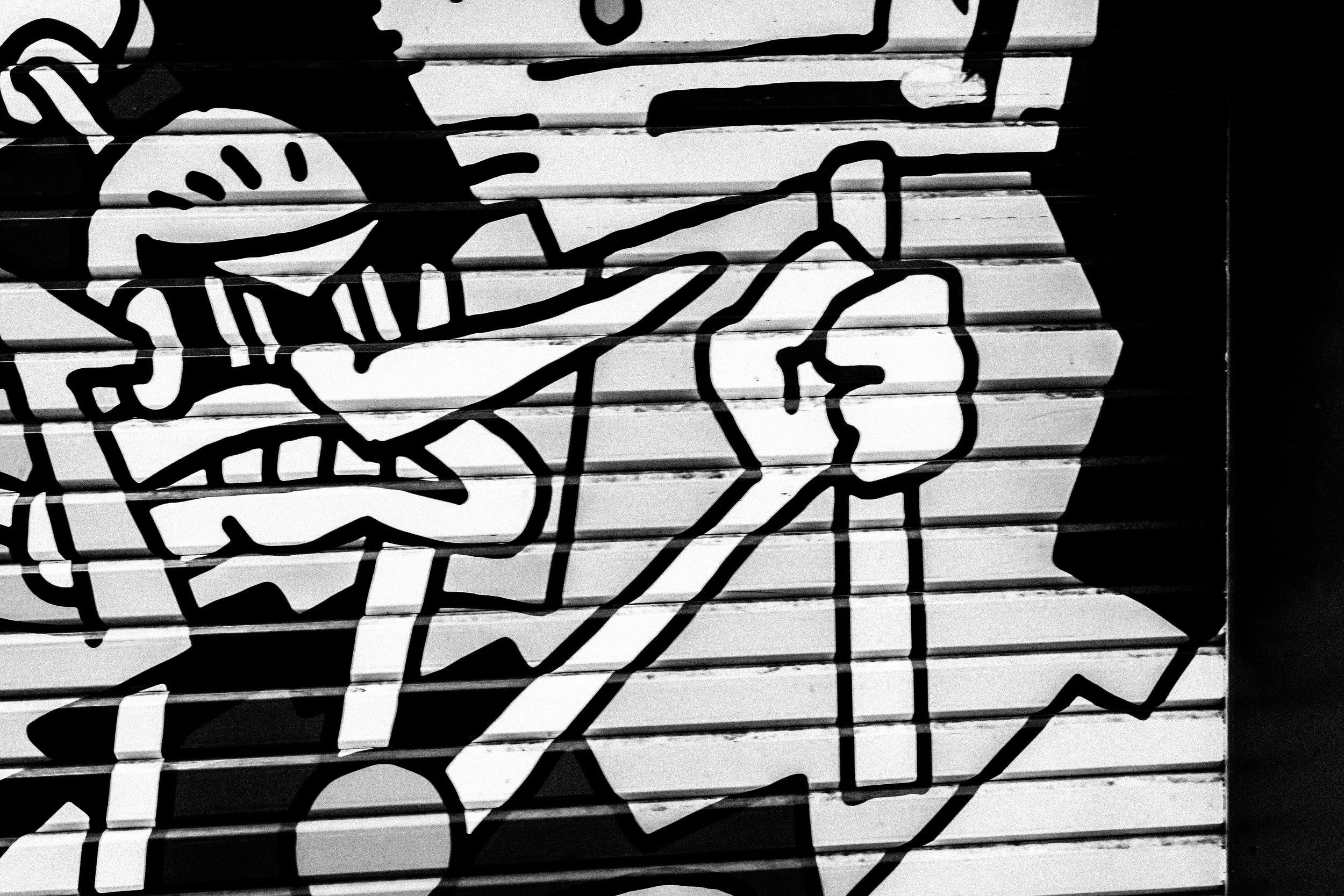 Black and white photo of abstract line art graffiti on a wall or surface.