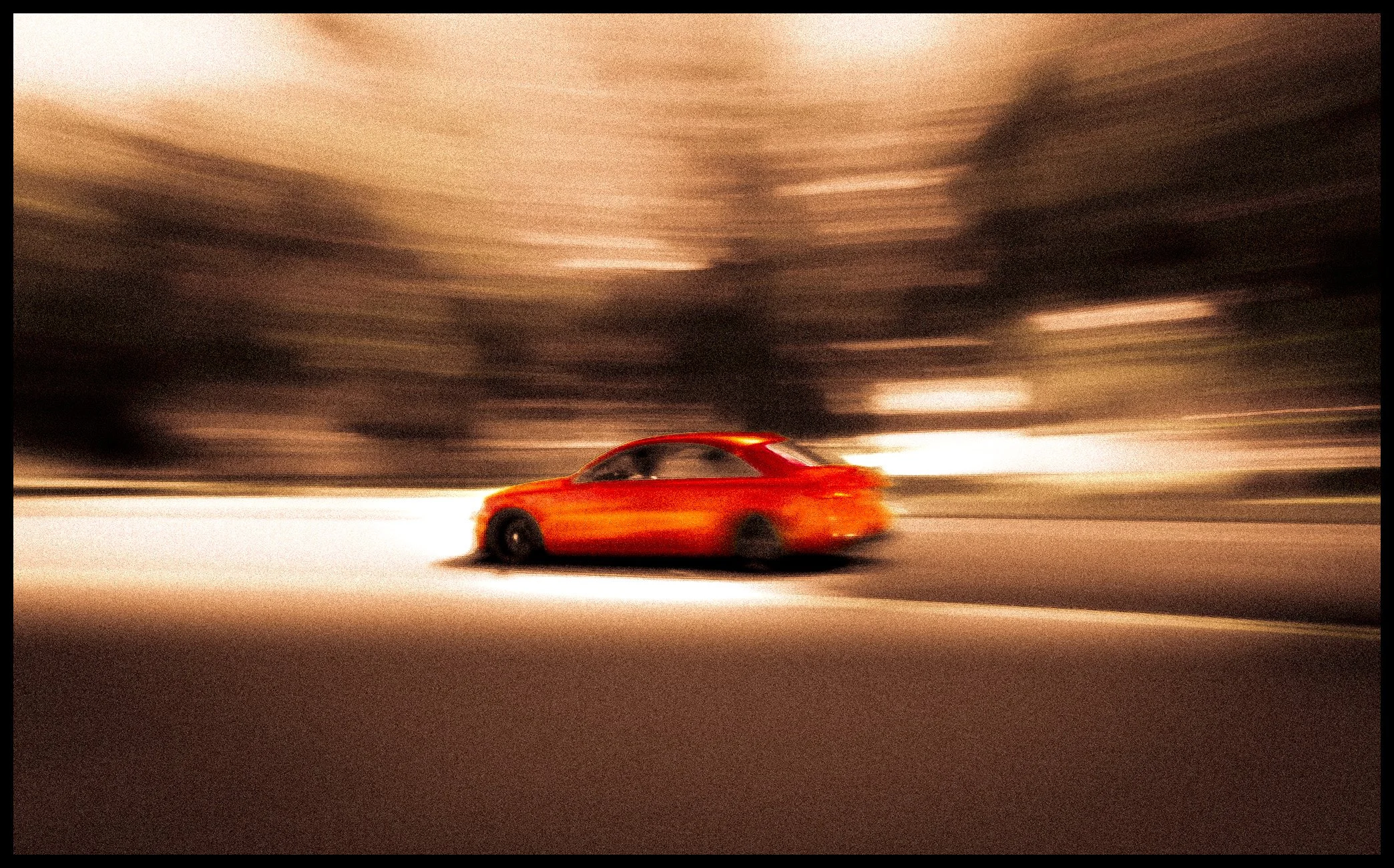 A red car driving on a road with a blurred background, indicating motion, in a high-speed motion shot.