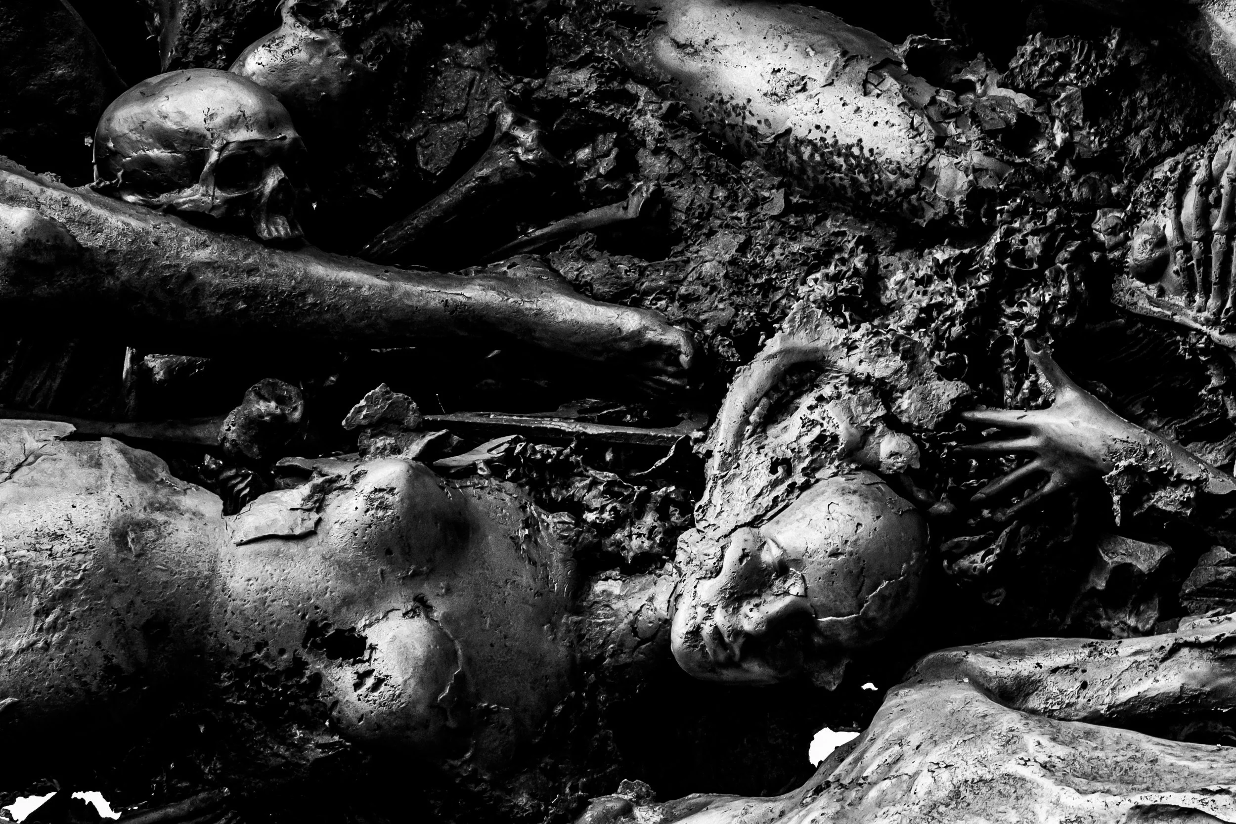 Black and white photograph of human skeletal remains scattered among dirt and debris.