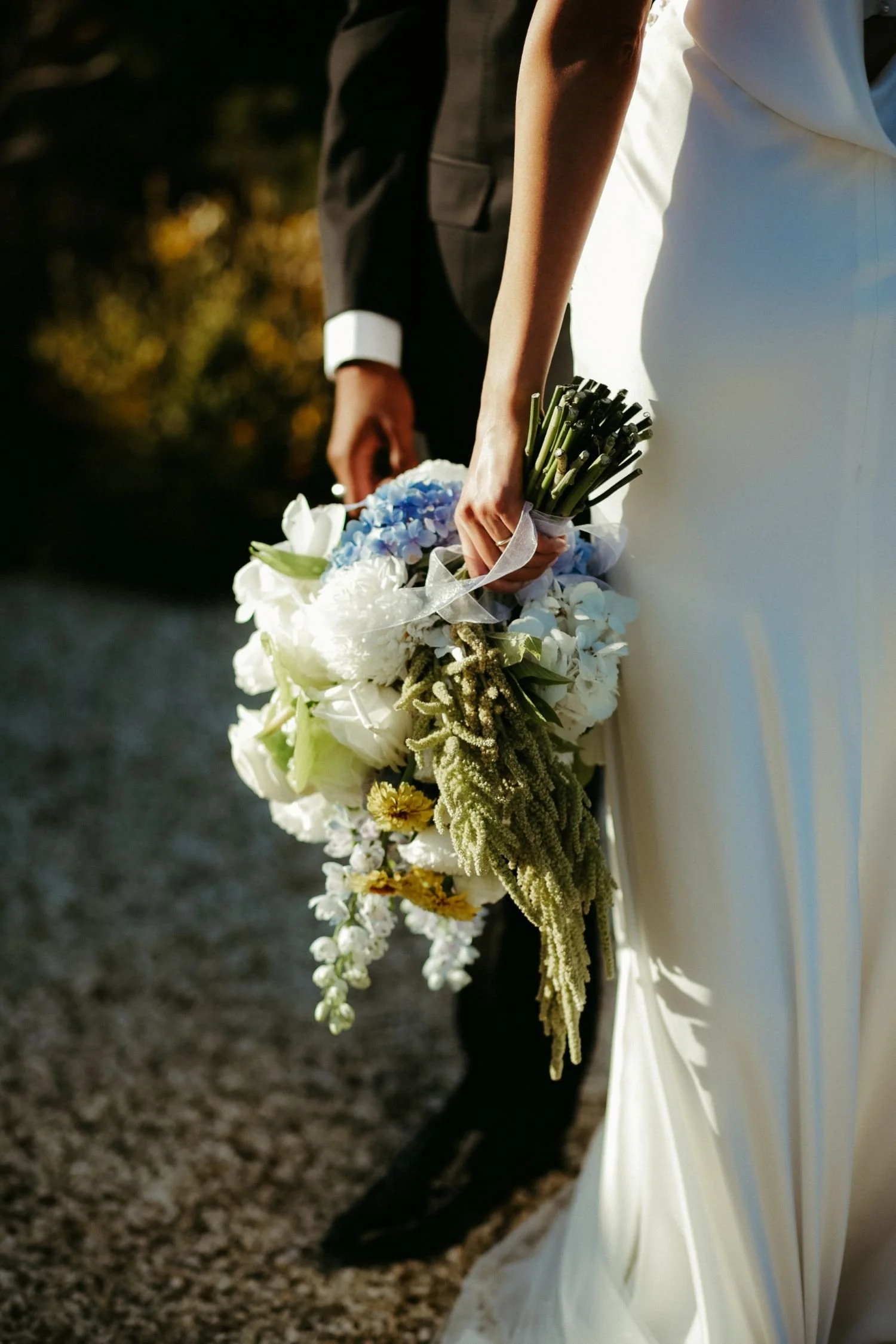 A bride holding a wedding bouquet with her groom standing behind her