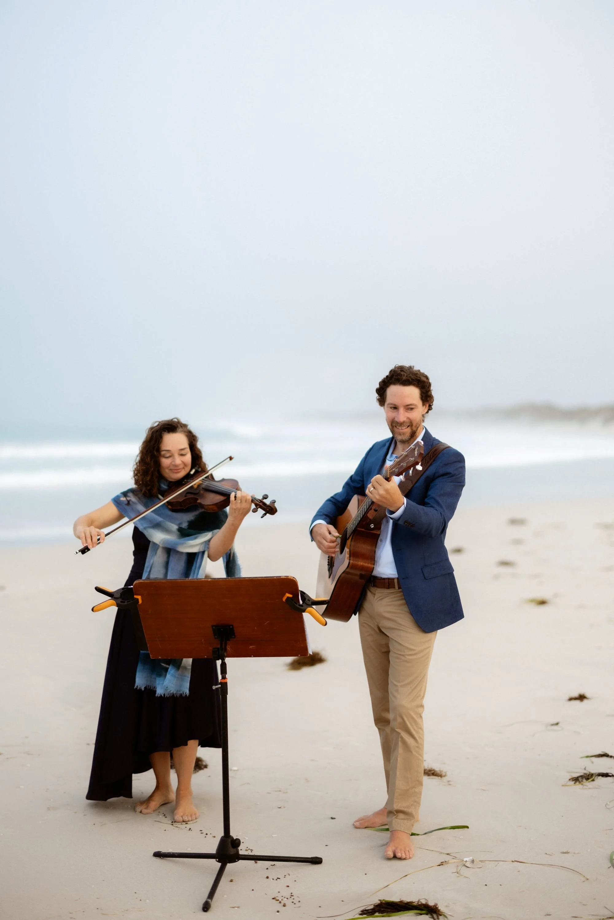 A proffesional musical duo playing together on the beach in WA