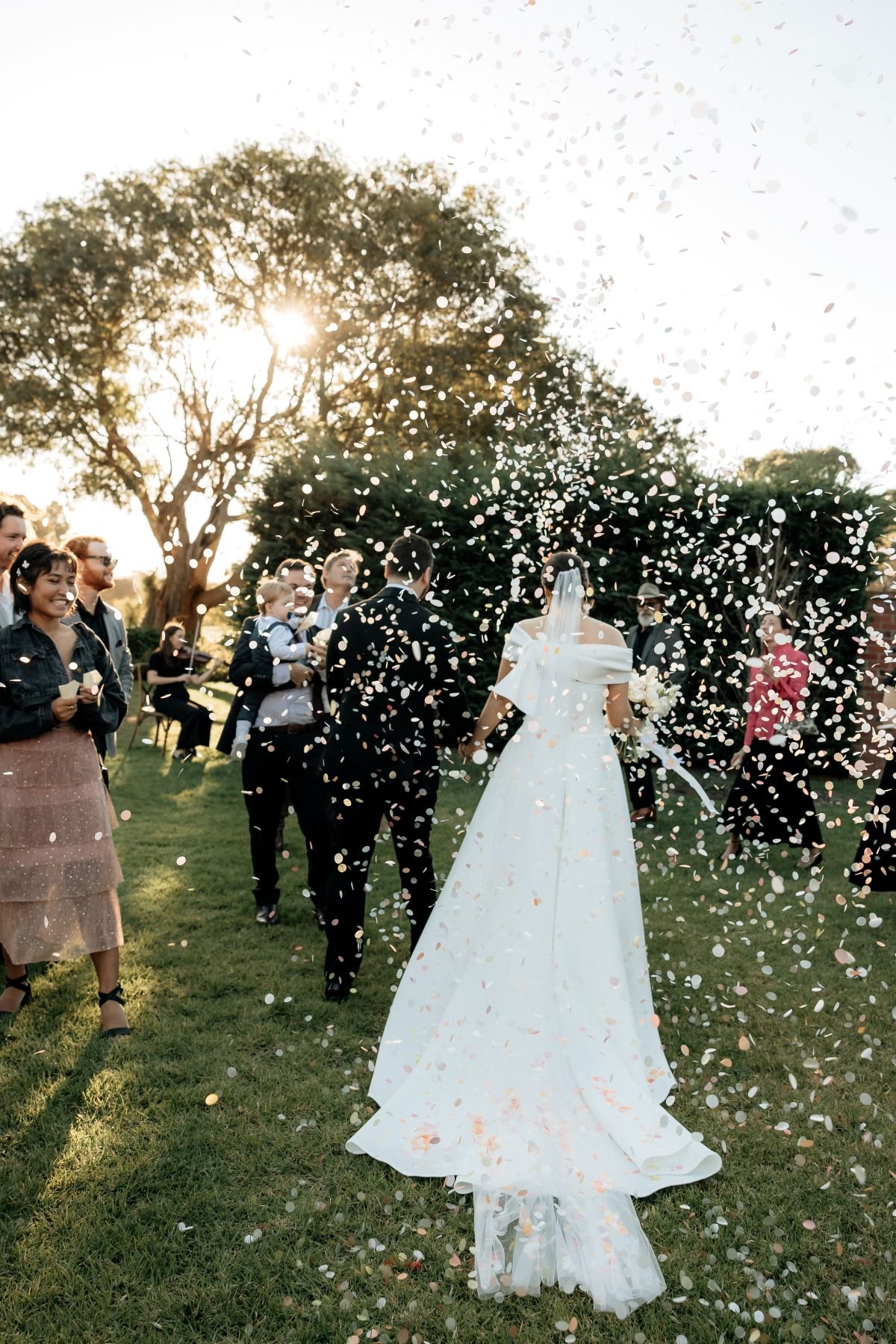 A bride and groom being showered with confetti as a live jazz band plays music
