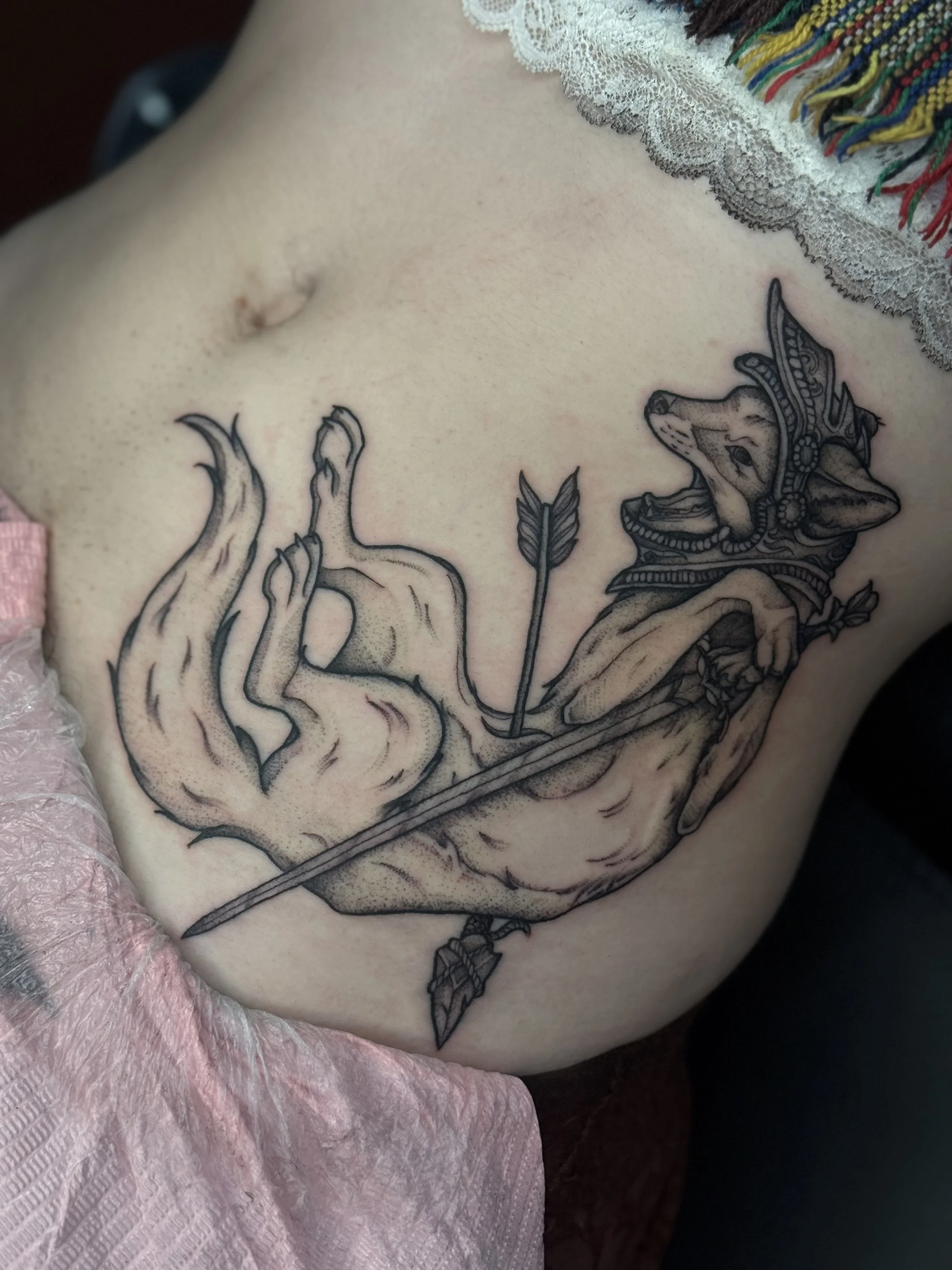 Medieval fox holding a sword stabbed with an arrow tattoo on the abdomen