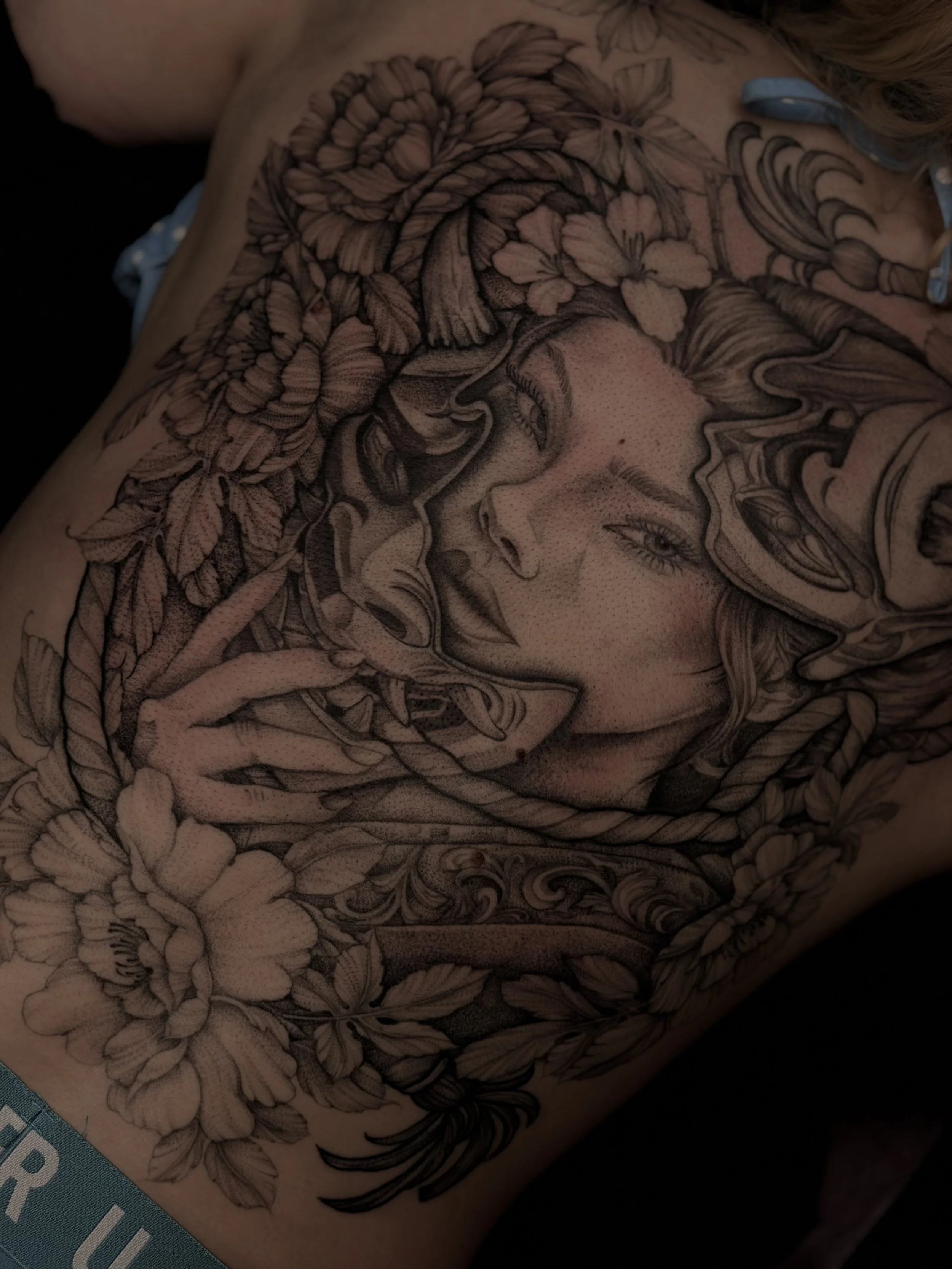 Geisha holding Hannya Mask with peonies on a woman's back.