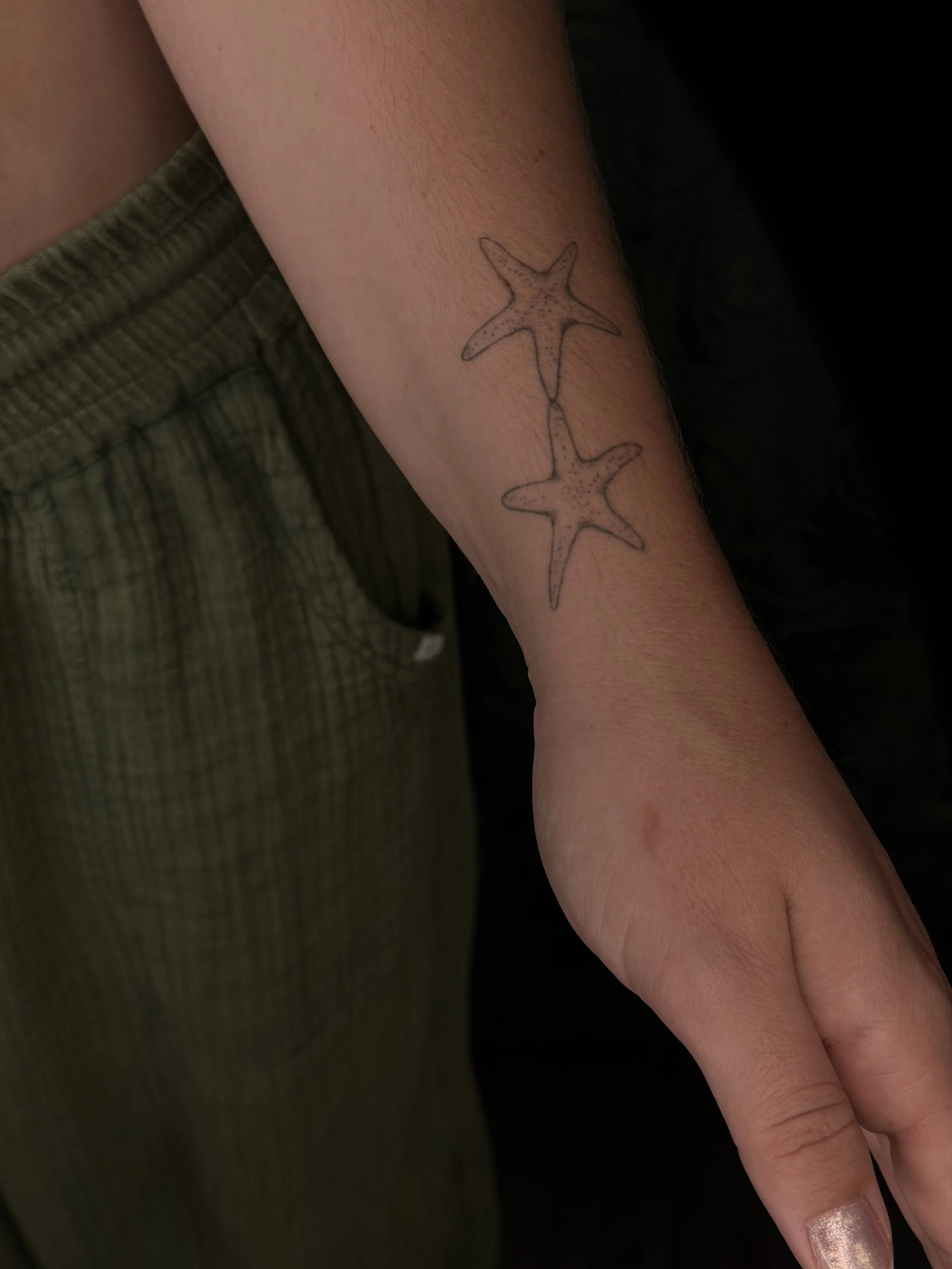 Two healed fineline starfish tattoos on wrist.