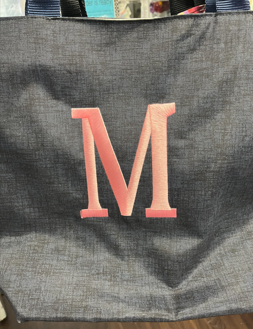 Black Demin bag with a pink embroidered letter M on the front.