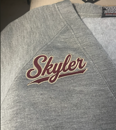 Gray cardigan with a maroon and Vegas gold thread embroidered "Skylar" on the right-hand chest area.