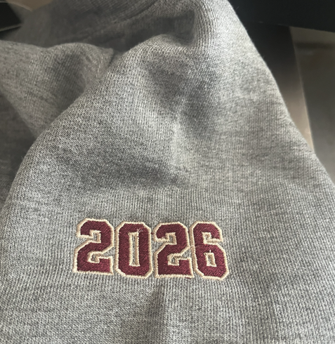Gray cardigan with a maroon and Vegas gold thread embroidered the year "2026" on the right sleeve.