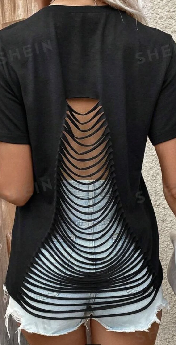 Person modeling a black T-shirt with a custom layered cutouts on the back of the shirt.