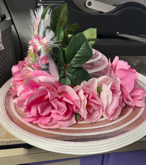 Pink Kentucky Derby hat with artificial flower arrangement with green leaves and decorative mesh. This hat was designed for a Kentucky Derby party.