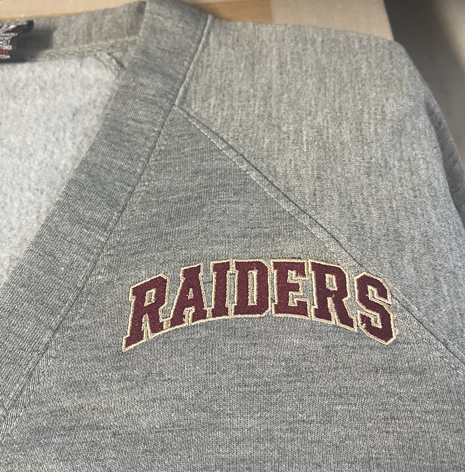 Gray cardigan with a maroon and Vegas gold thread embroidered "Raiders" on the left-hand chest area.