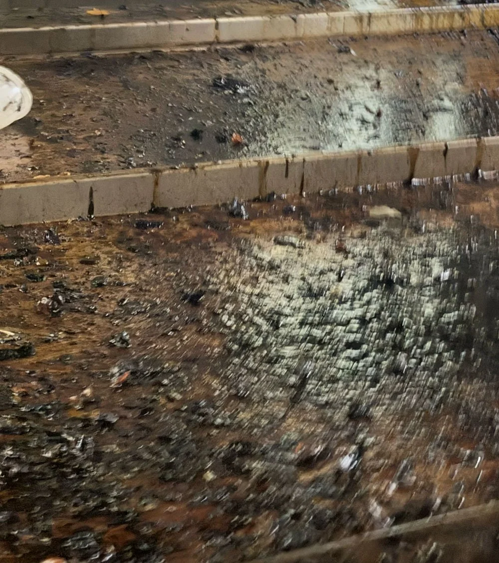 Empty ashtray with ashes and cigarette butts on a wooden table.