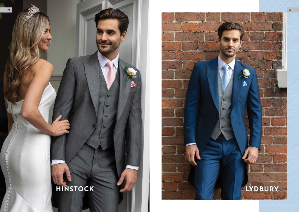 Two men in suits, one in a gray suit with a pink tie and boutonniere, the other in a blue suit with a gray waistcoat and boutonniere, standing against brick walls.