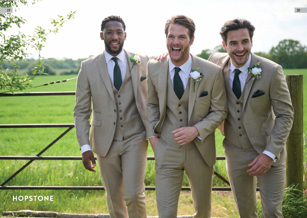Three men in beige suits with white shirts and dark ties standing outdoors by a wooden fence, smiling and enjoying a sunny day in a green field.