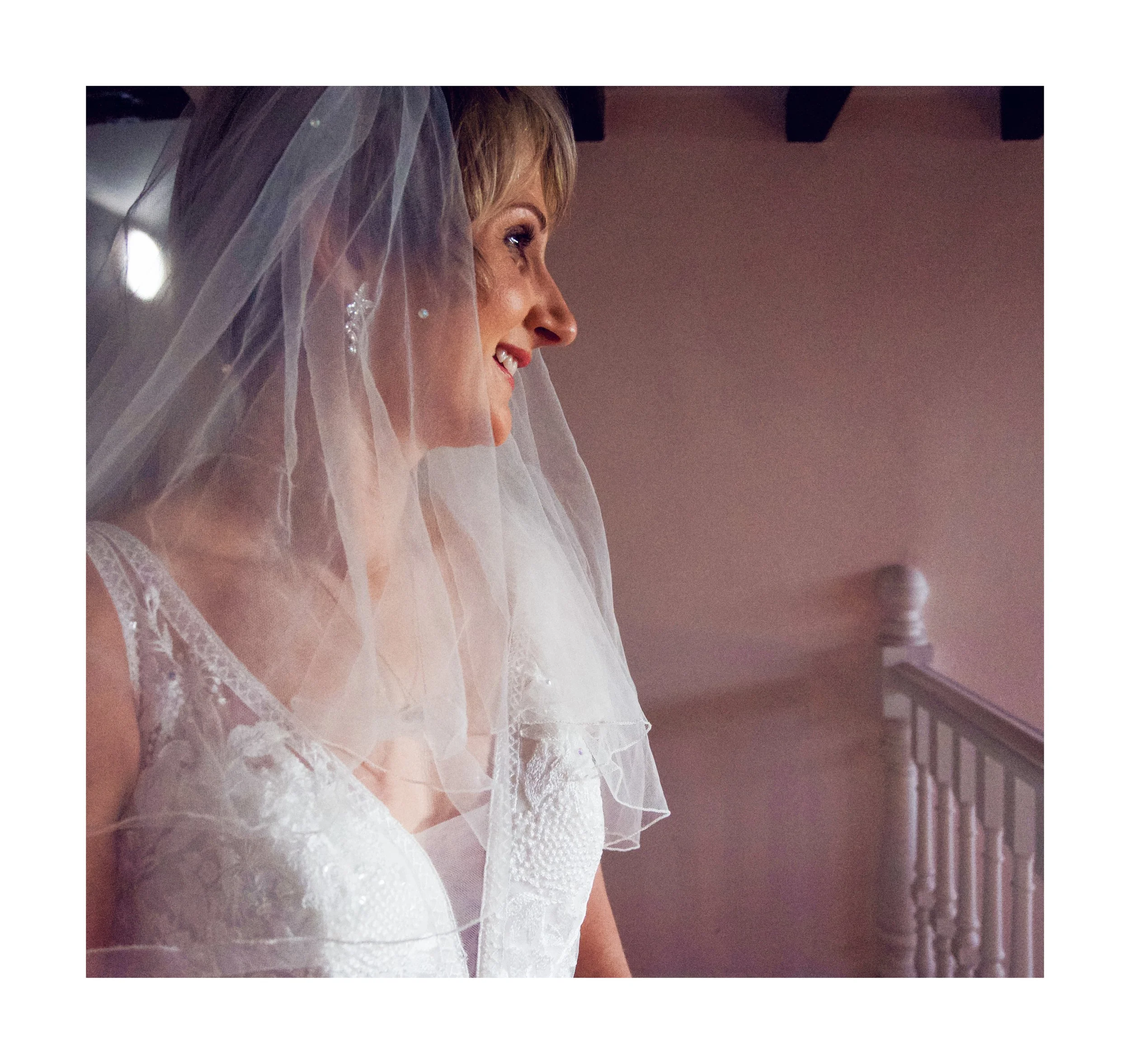 Bride is smiling. Close up of dress reveals beautiful embroidered floral detail.
