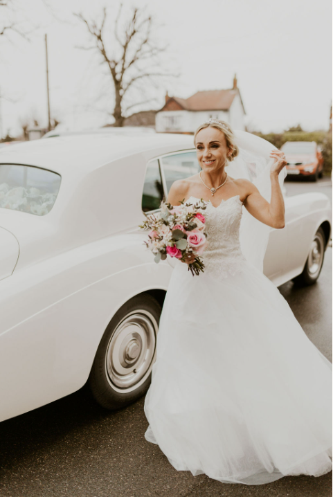 A vision of bridal beauty. The bride looks radiant as she gets out of the wedding car.