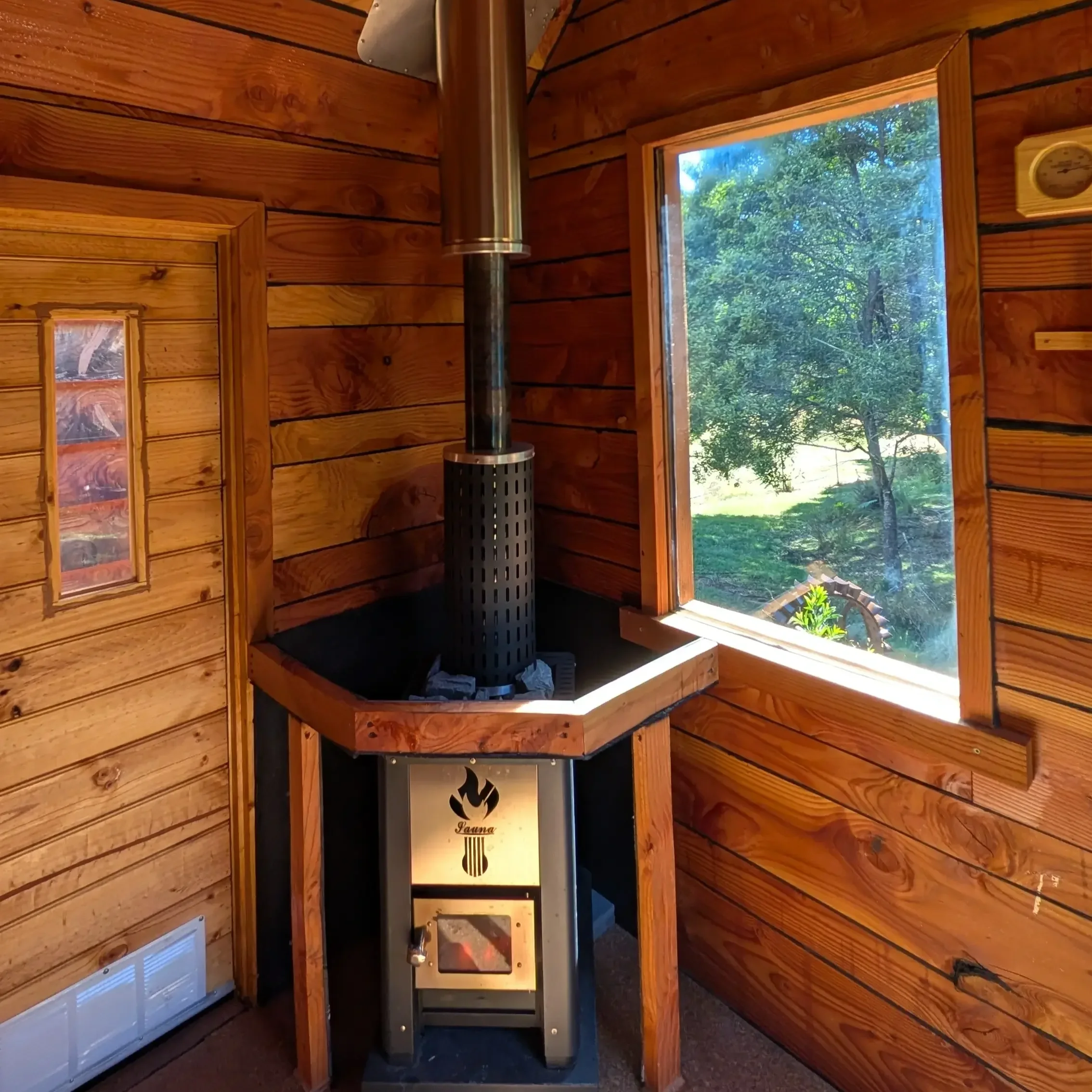 The private, wood-fired sauna with lush bush views out of window at tailrace sauna. Located near Derby, Northern Tasmania