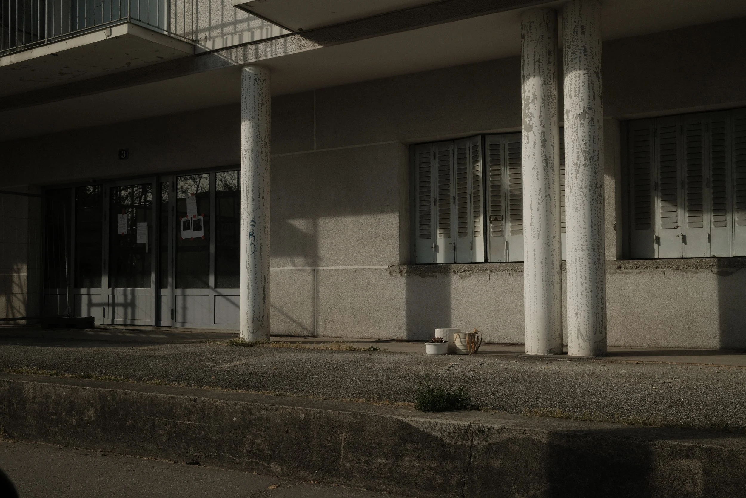 FArchitectural photography of a concrete façade with inclined pillars and closed shutters. Play of light and shadows.