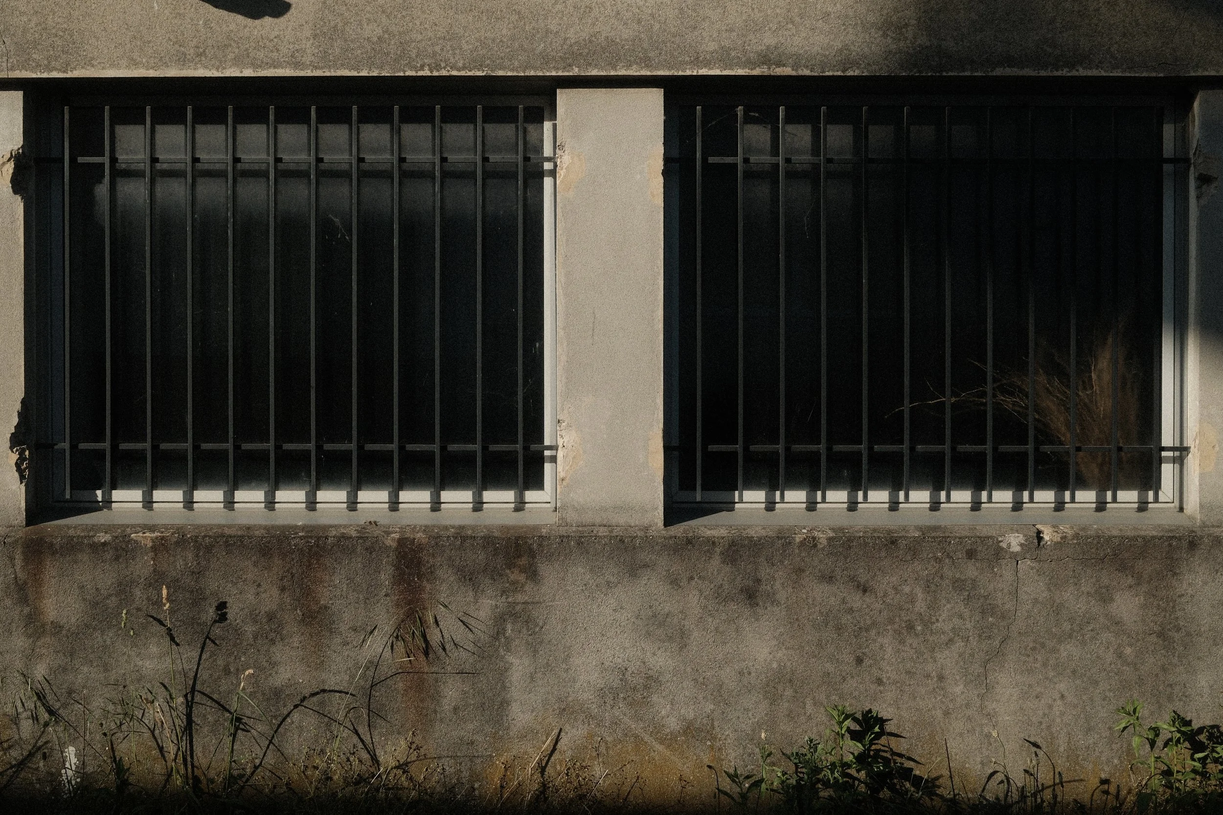 Symmetry and repetition in urban architecture. Concrete wall with barred windows and natural textures. Minimalist urban landscape.