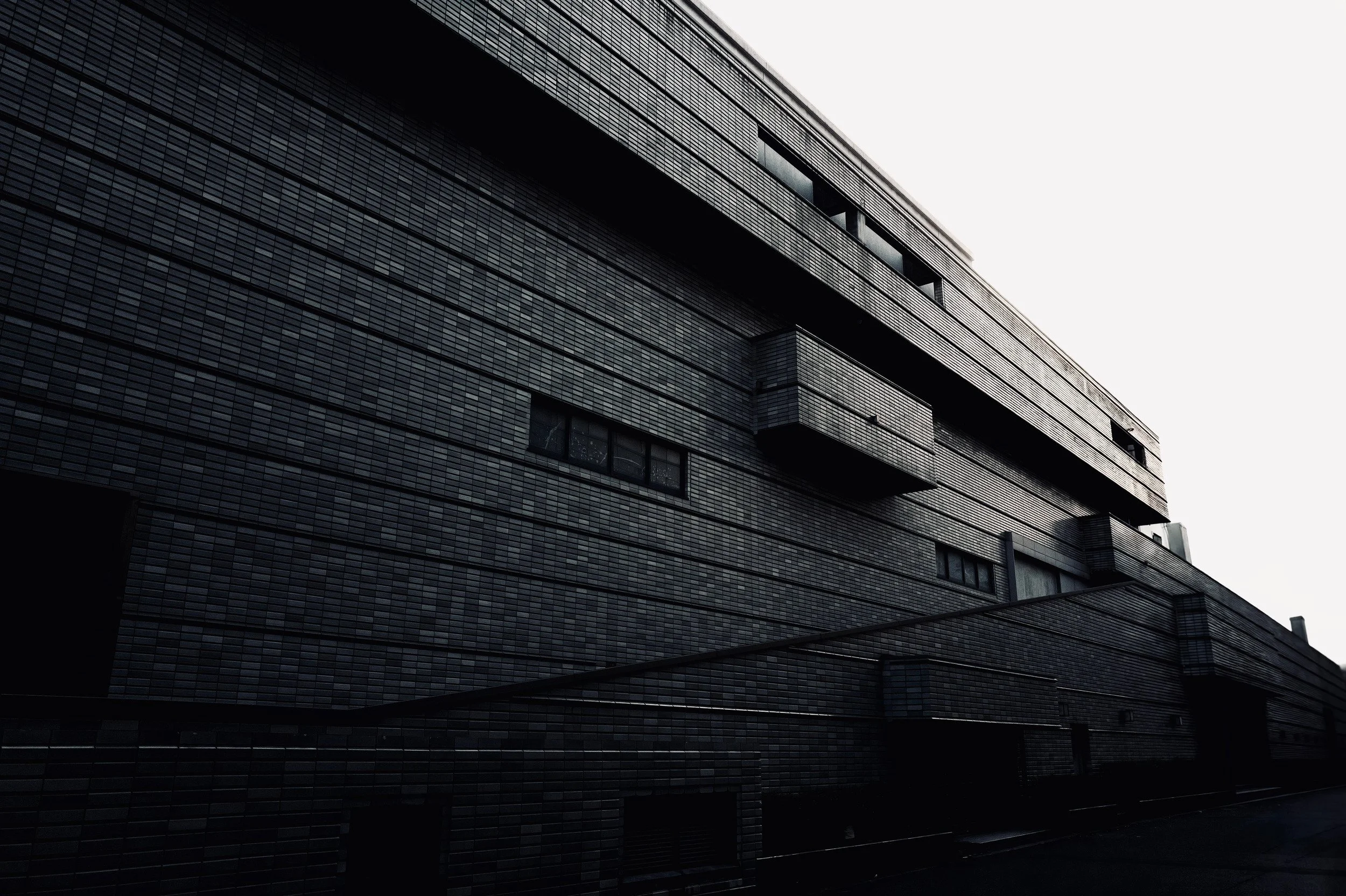 Dark tiled architectural masses, projecting rectangular volumes and a rising diagonal ramp.