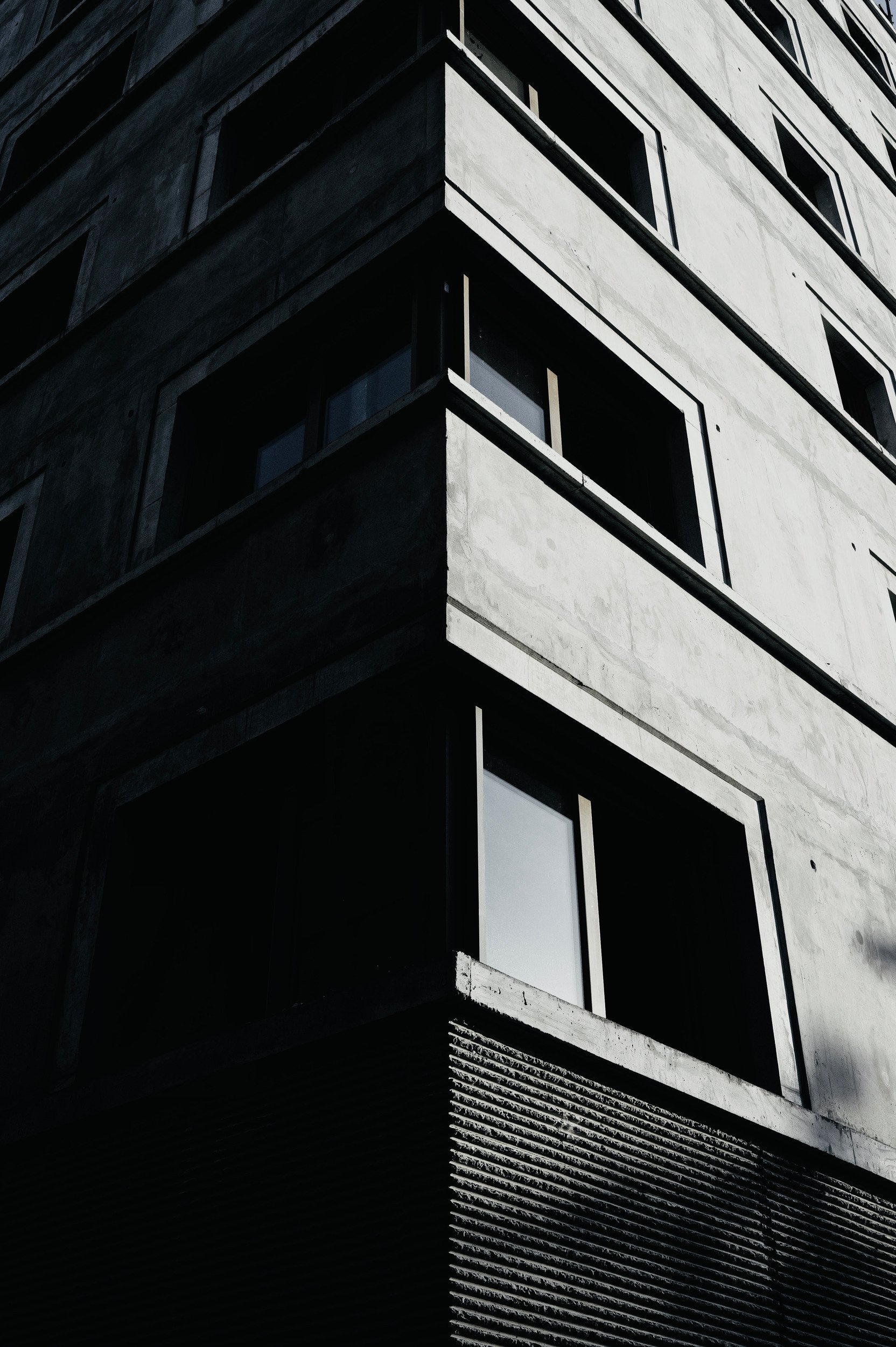A concrete building corner dividing a sunlit facade from deep shadow.