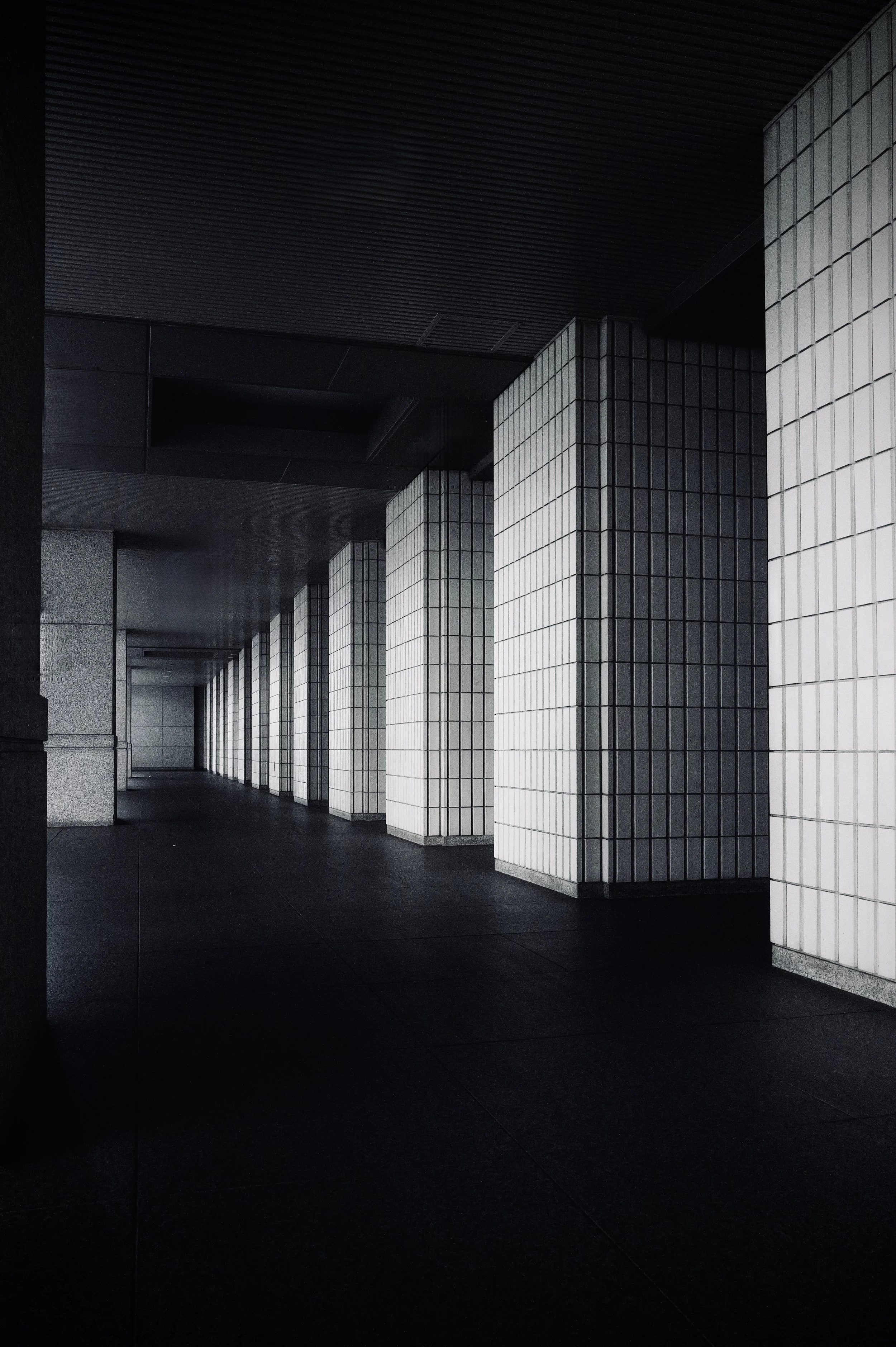 Perspective view of a modern building corridor with repetitive white tiled columns - Minimalist and graphic urban photography