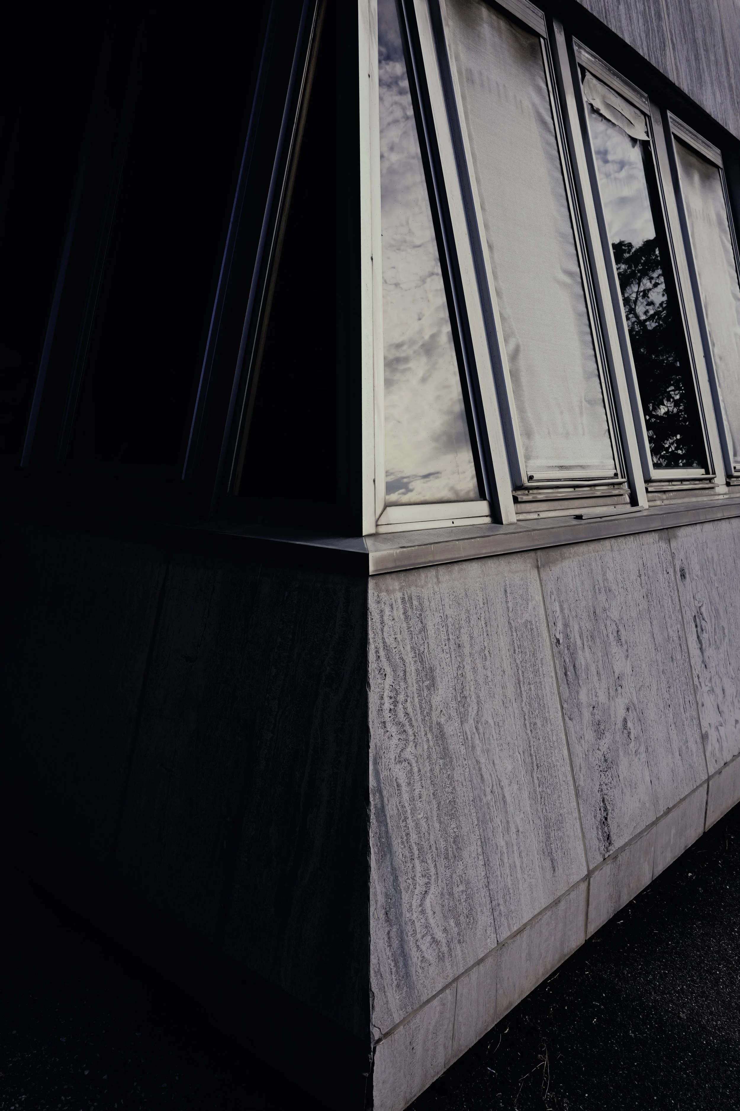 Geometric view of a modern concrete building with aluminum windows. Reflections of the sky and architectural lines.