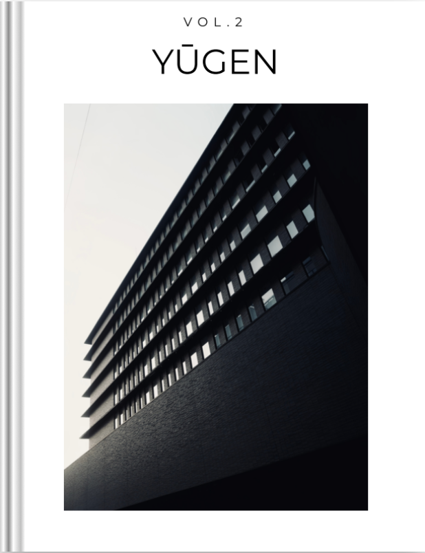 A modern high-rise building with dark exterior and numerous windows, viewed from below against a light sky. The top of the image shows the text 'VOL.2 YÜGEN' in black lettering.
