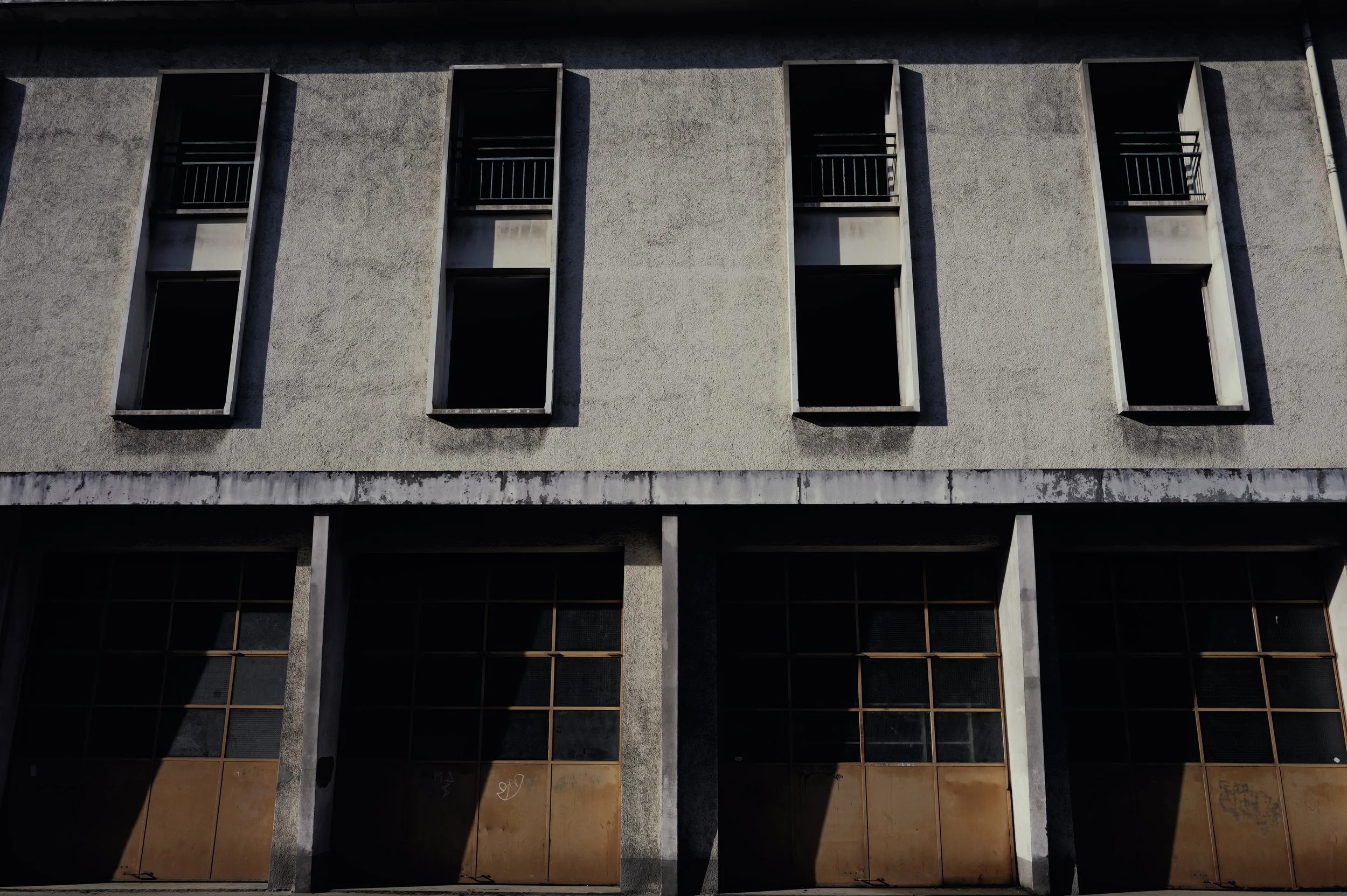 Detail of a weathered concrete building with open windows and wooden panels. Gritty urban aesthetic and structure.