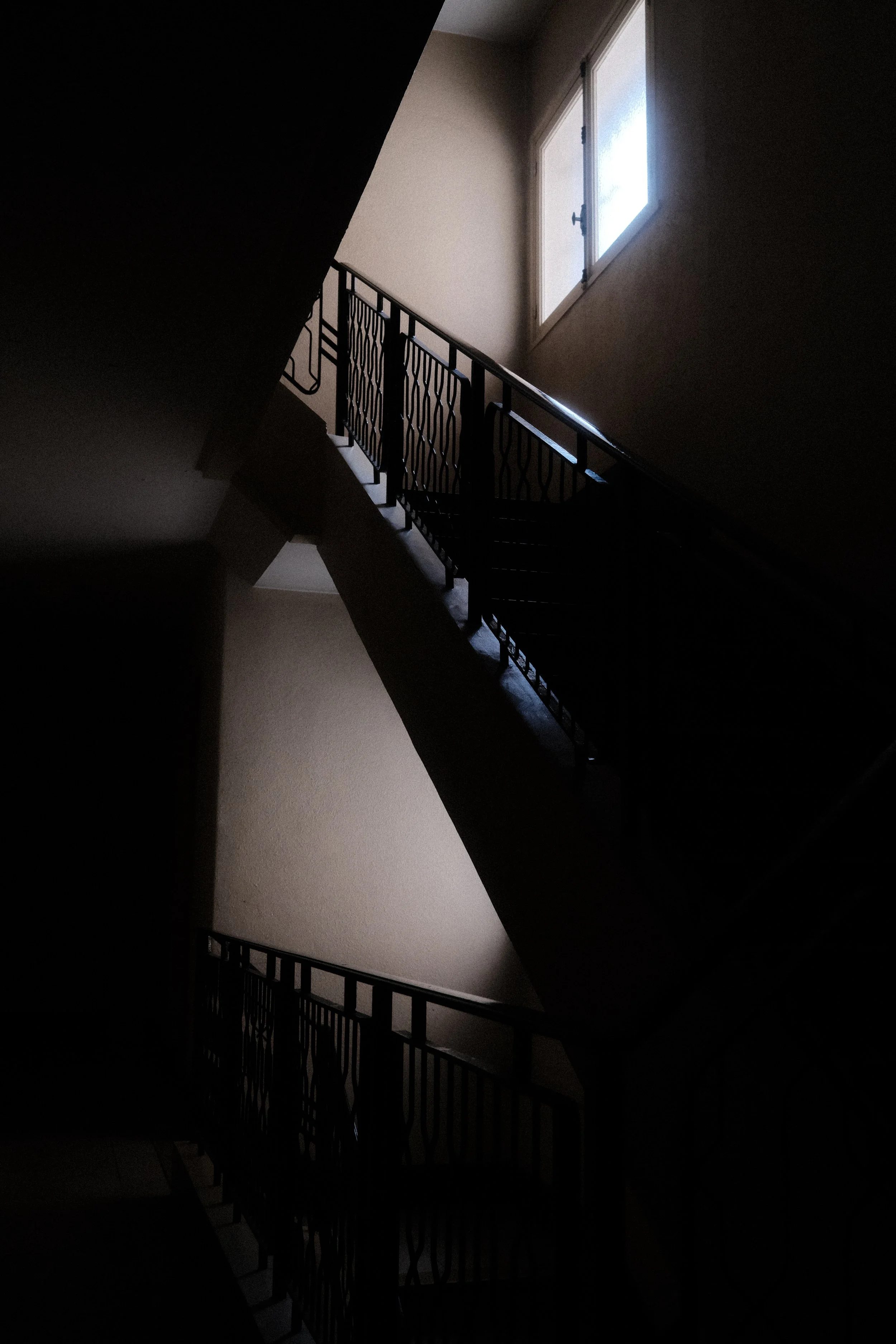 Low light architectural photography of a staircase with dramatic natural light. Chiaroscuro effect in urban interior.