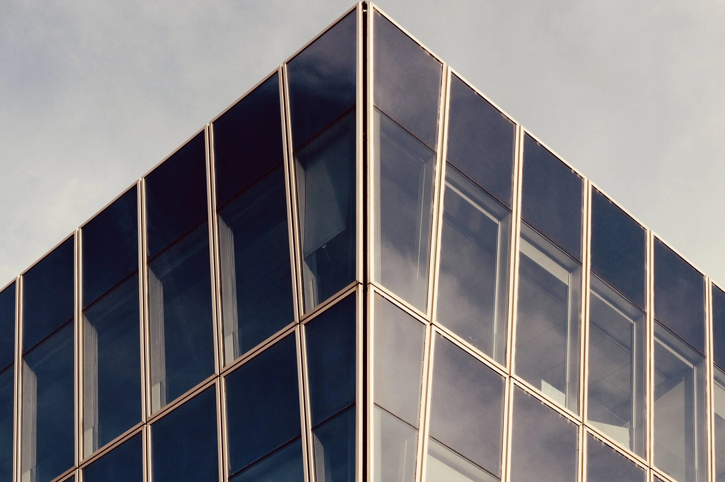Abstract urban photography of a modern glass building with chevron patterns and reflections. Focus on geometry and structure.