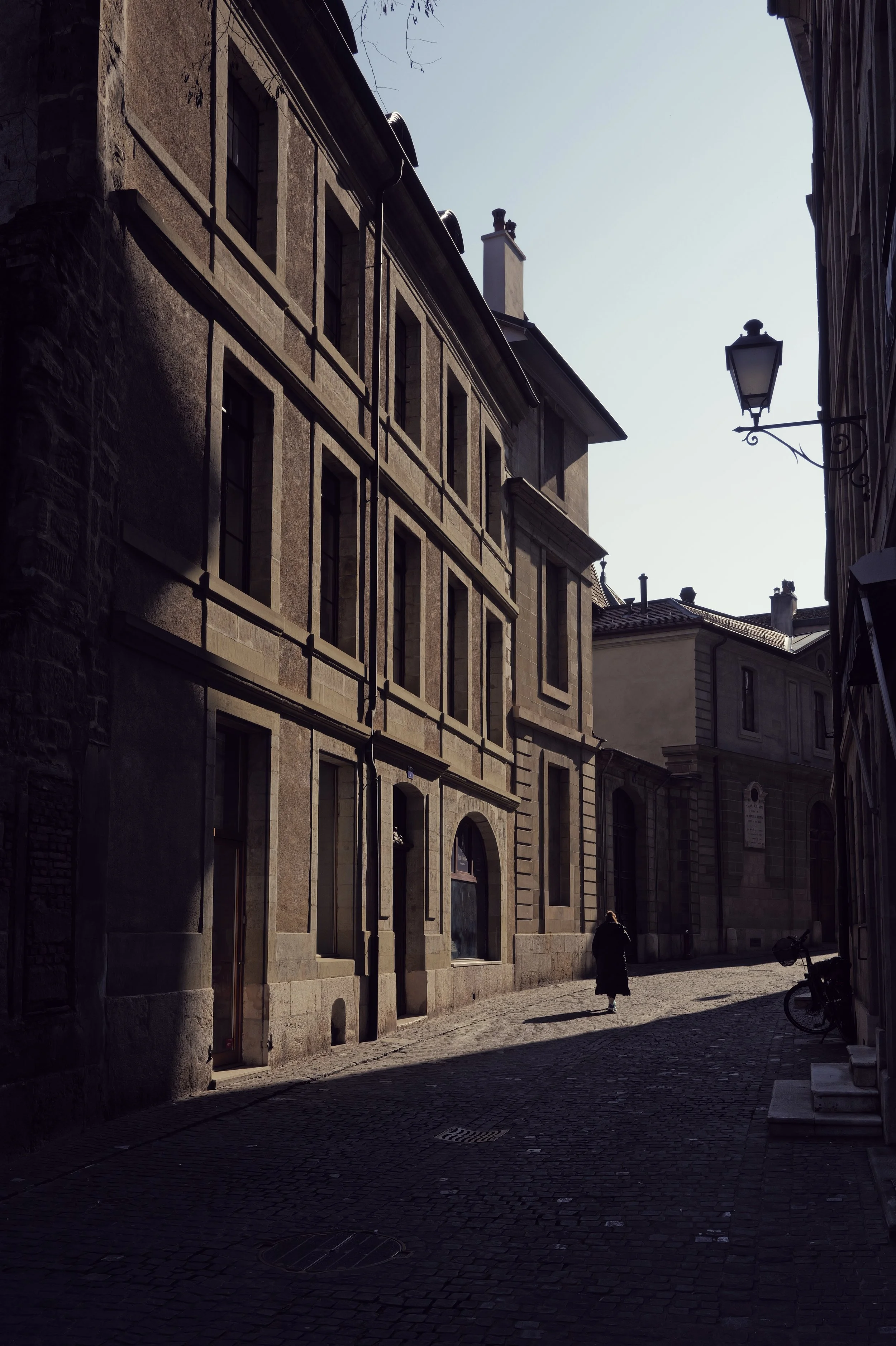 Street photography of a European stone alley. Atmospheric urban scene with old architecture and deep shadows.