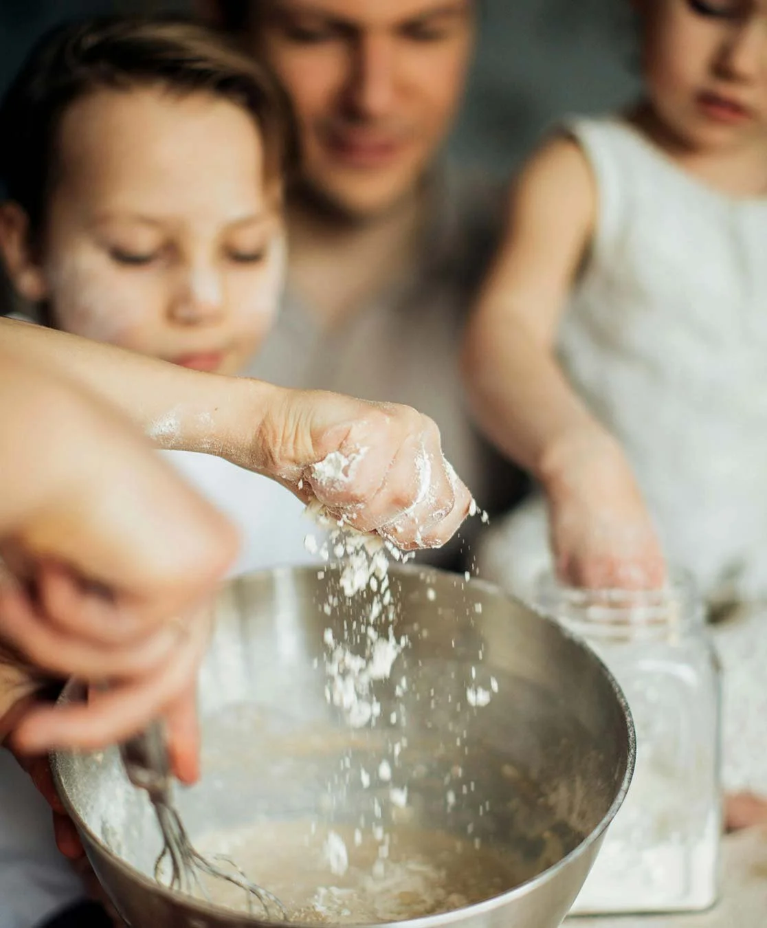 Organise & Harmonise. A family baking together, with a young boy and an adult, adding flour into a mixing bowl.