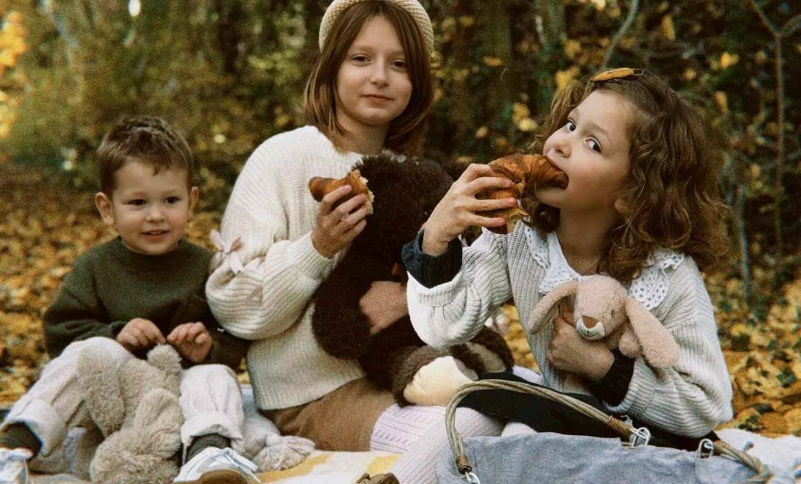 Organise & Harmonise. Three children sitting and having a family picnic.