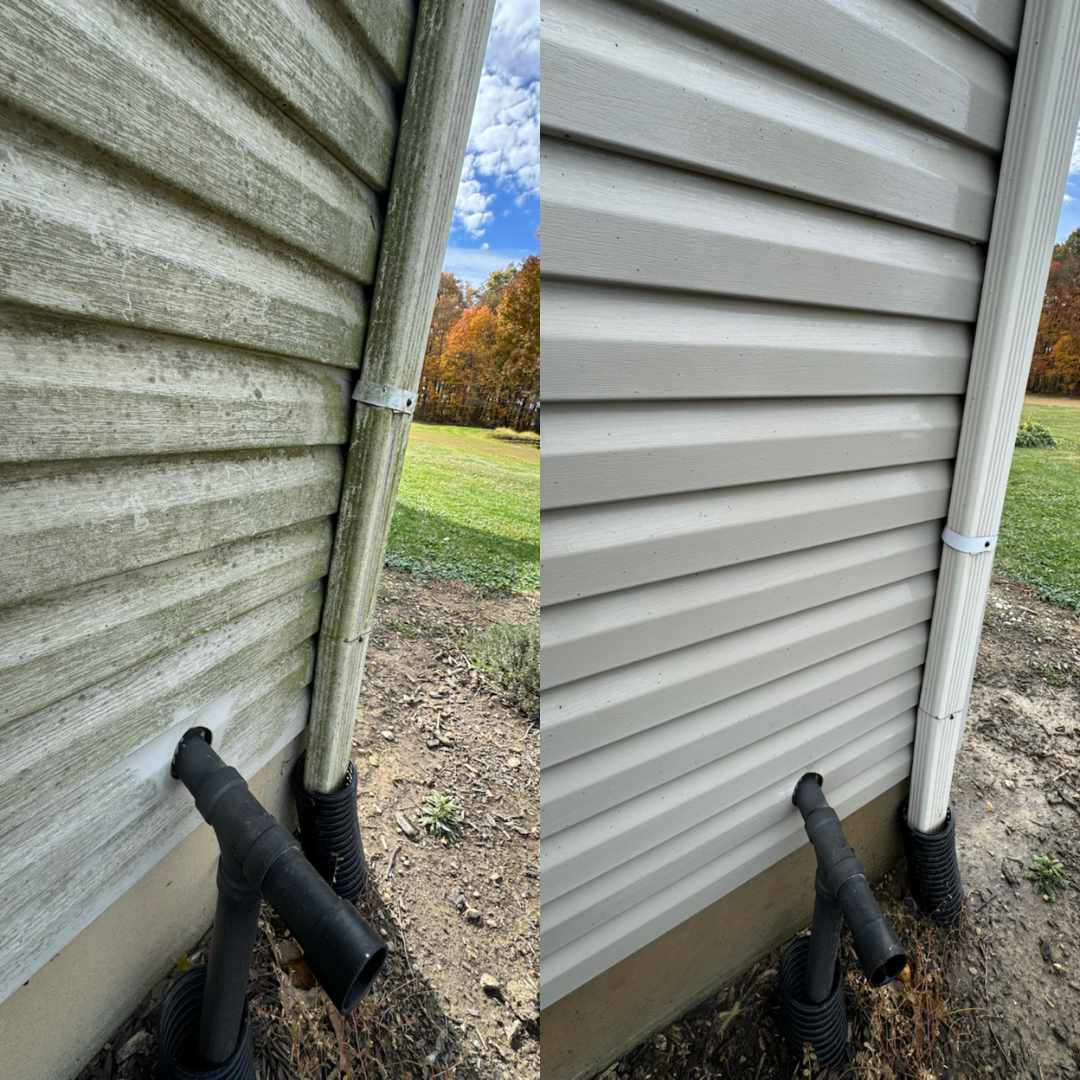 Side view of house exterior showing before and after siding cleaning, with new gray siding installed, drainage pipes, and outdoor grass and trees in background.