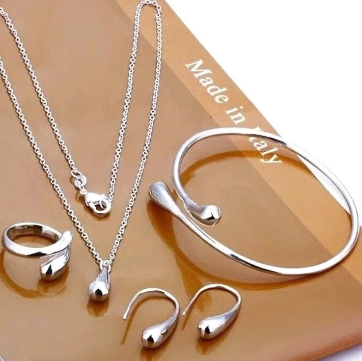 Ensemble de bijoux en argent comprenant un collier à deux chaînes, un bracelet ouvert, une boucle d'oreille, une bague et un pendentif en forme de goutte.