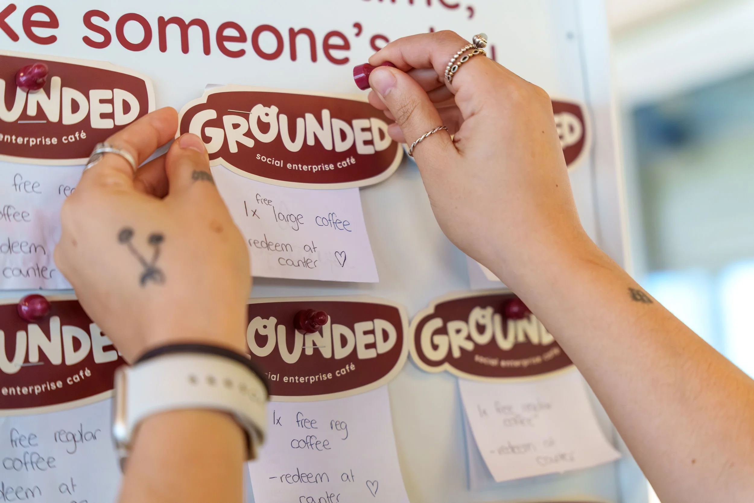 Hands placing a pay it forward free coffee on wall