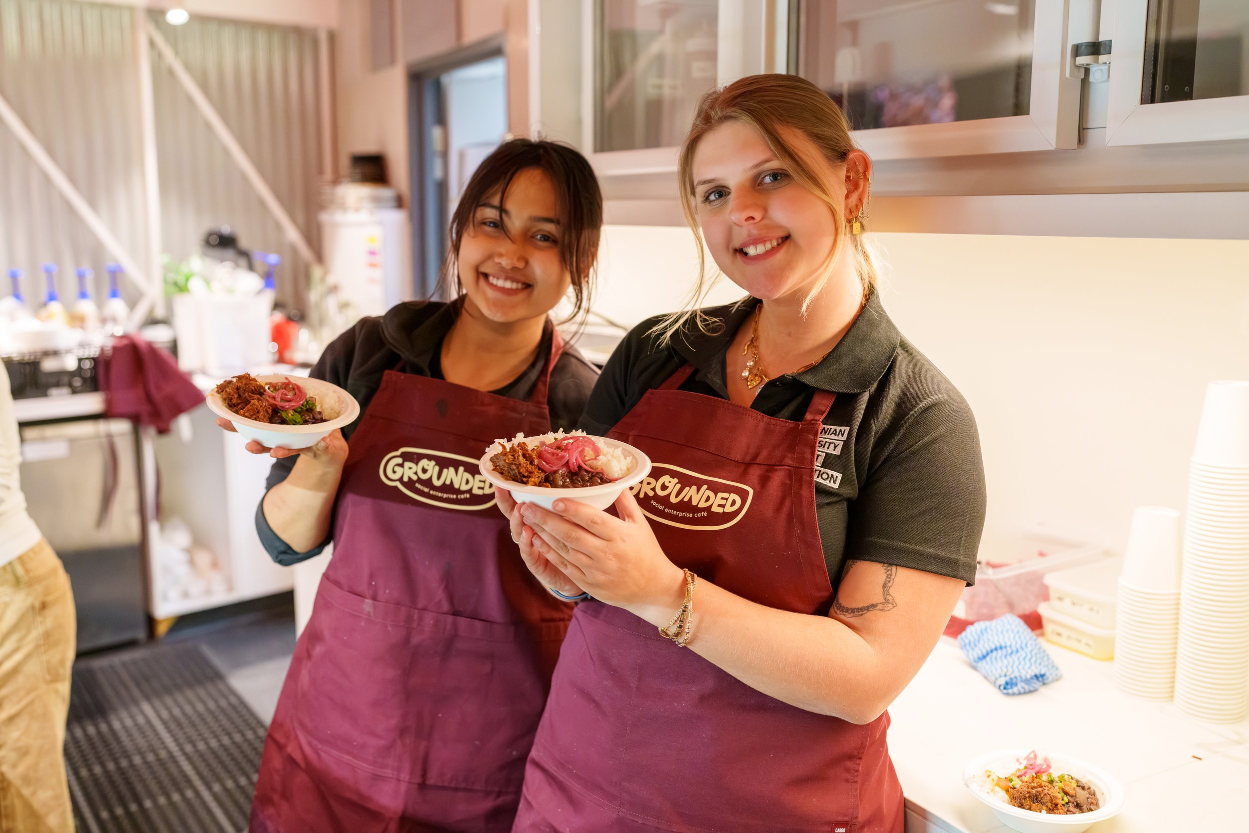 Two people holding meals whilst smiling