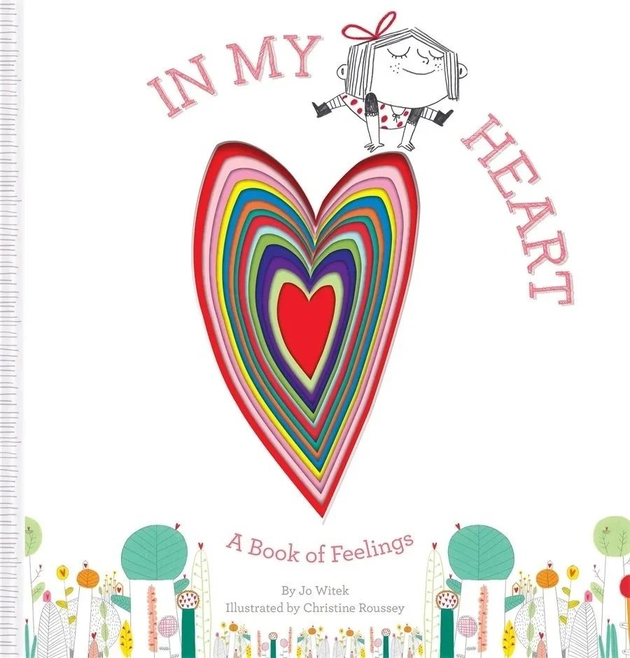 Cover of a children's book titled 'In My Heart: A Book of Feelings' featuring a colorful heart with layered rainbow colors and a smiling girl with outstretched arms and closed eyes at the top.