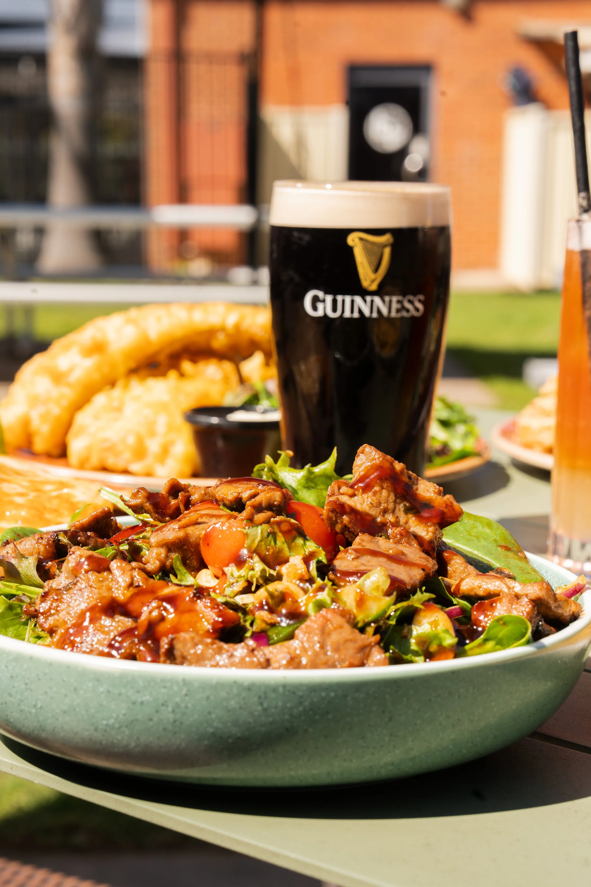 Meat salad with green leaves served with a pint of Guinness on a sunny terrace
