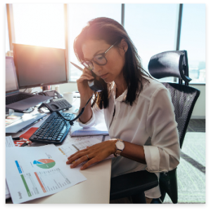 Businesswoman in office, talking on phone, working with documents and charts.