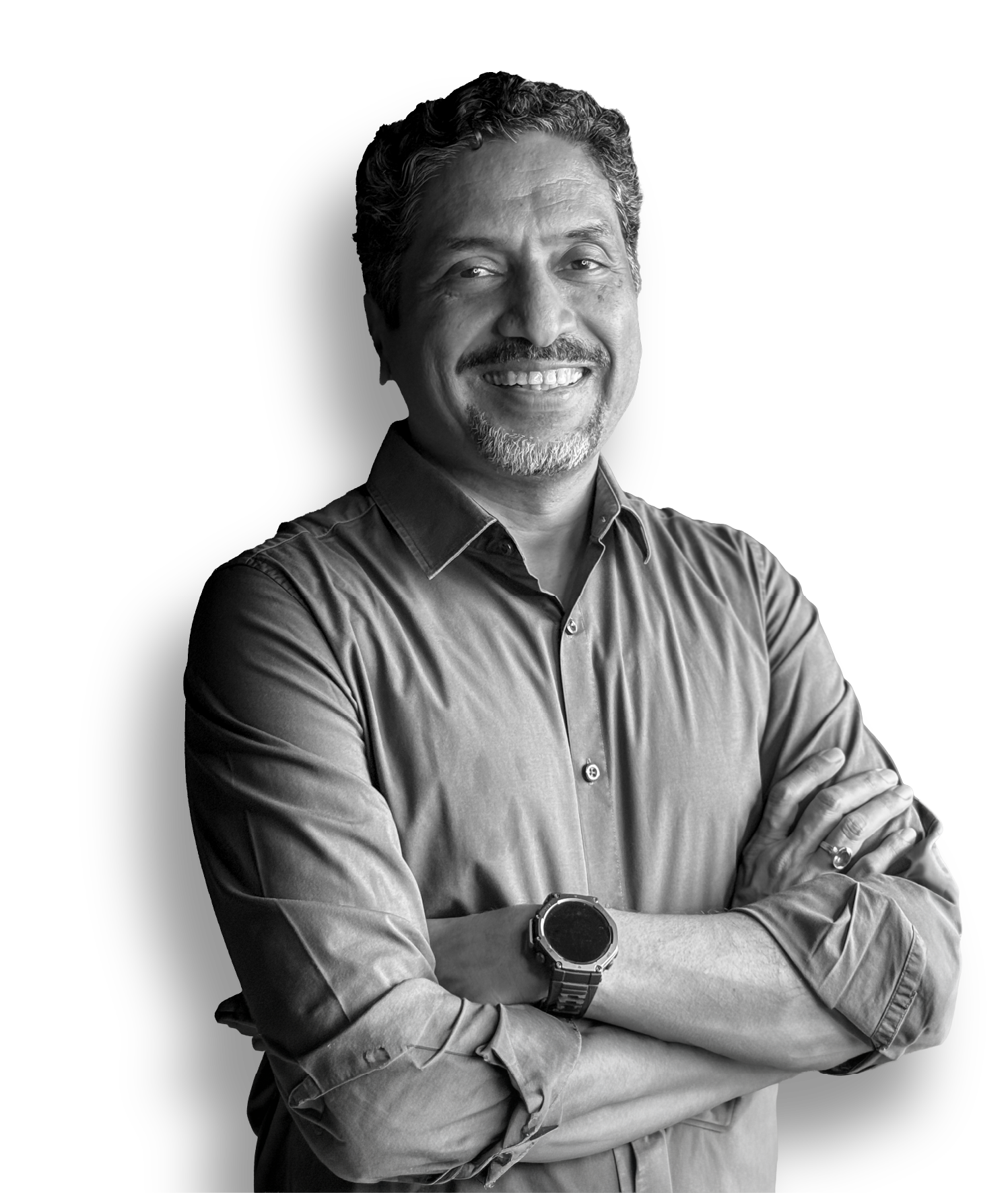 Black and white portrait of a smiling middle-aged man with curly hair and a beard, wearing a button-up shirt and a watch, with arms crossed.